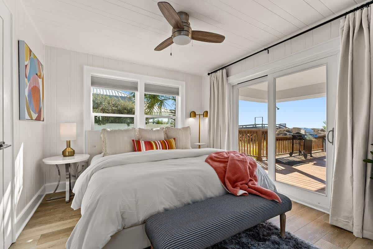 9620 Beach Blvd – Bright bedroom with a queen bed, window views, and access to a deck with grill.