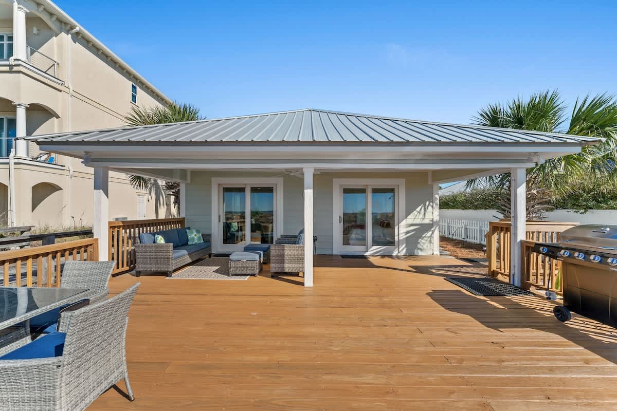 9620 Beach Blvd – Covered deck with outdoor seating, grill, and views of surrounding greenery and buildings.