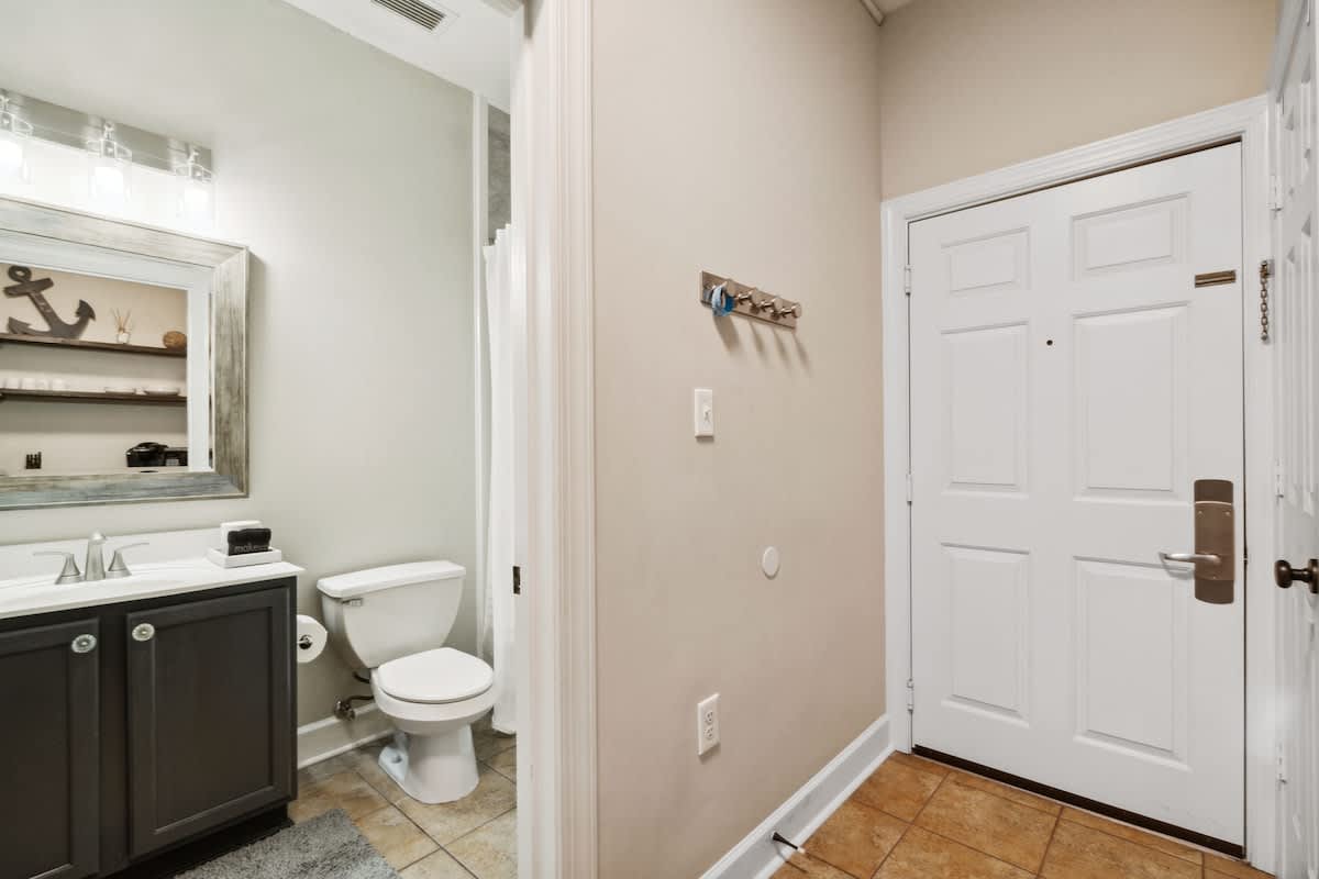 Village of SW B204 – Entryway with bathroom featuring sink, toilet, and an anchored mirror.