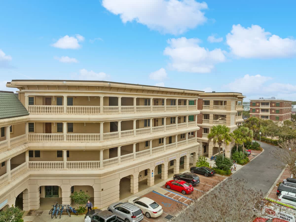 Village of SW B204 – Exterior view of a multi-story vacation rental with balconies, palm trees, and parked cars.