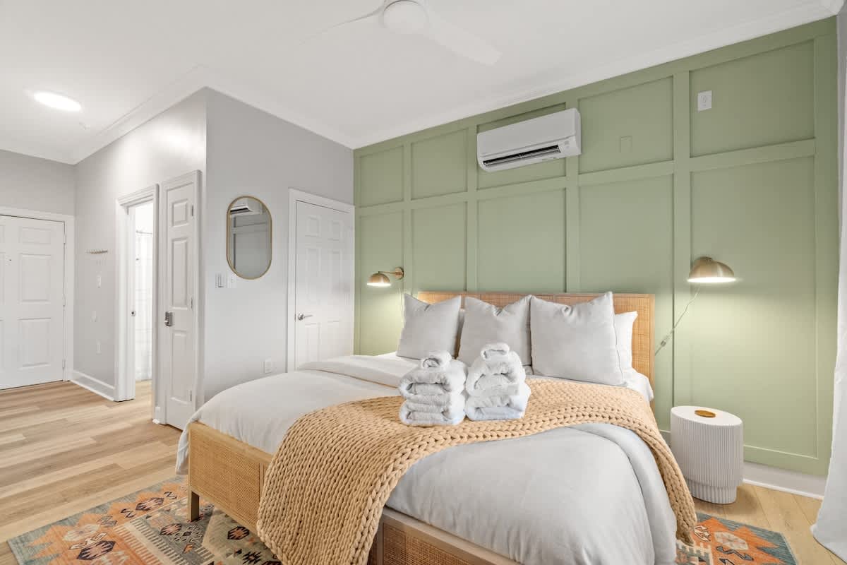 Village of SW B203 – Cozy bedroom with a green accent wall, a queen bed, and decorative towels on the blanket.