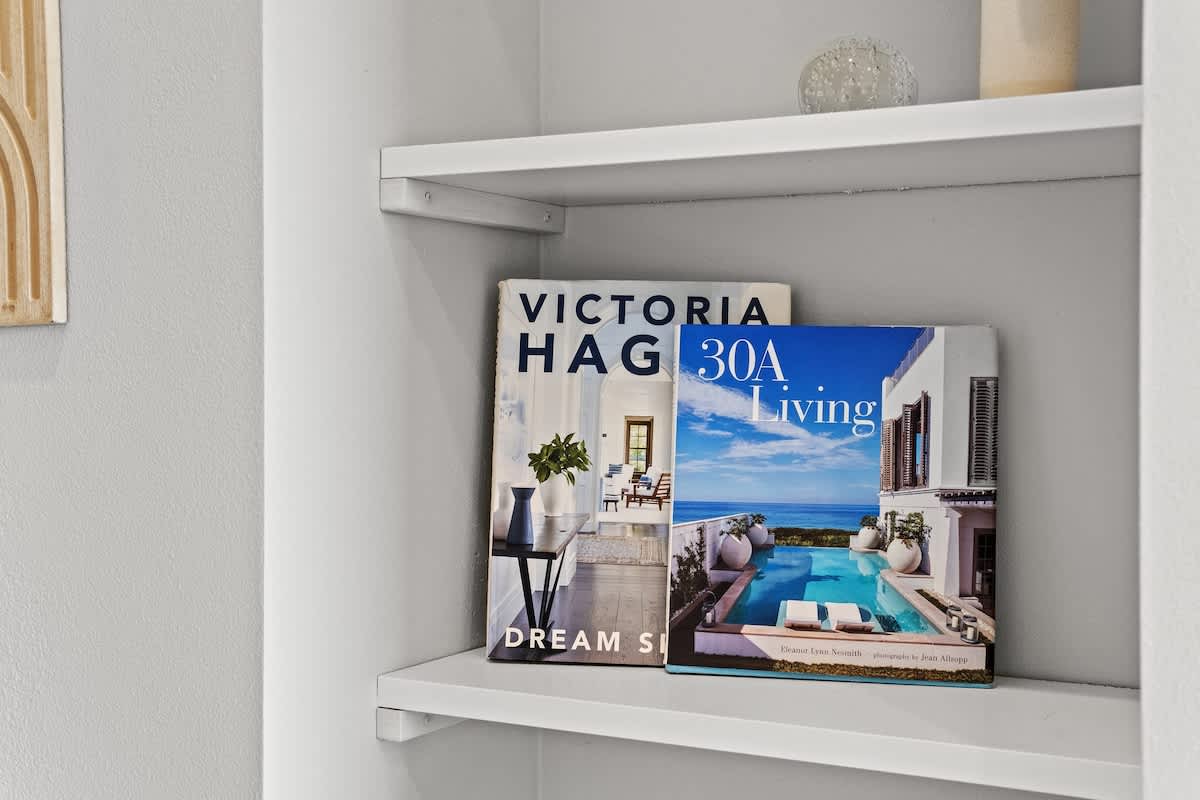 Inn at Seacrest 409 – Shelving with two magazines, "Victoria Hagan: Dream Spaces" and "30A Living," against a light gray wall.