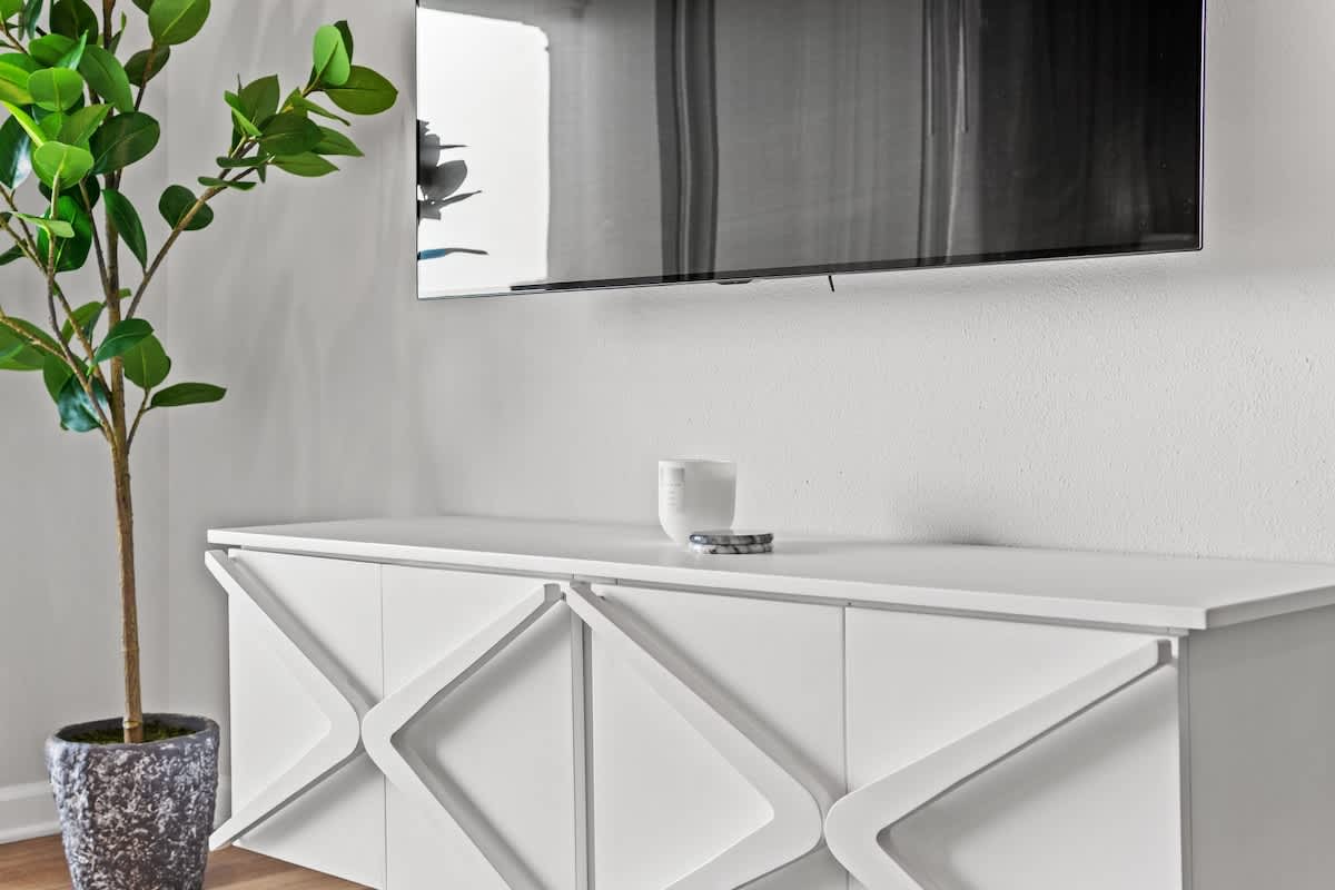 Inn at Seacrest 409 – Living room with a white cabinet, flat-screen TV, and a potted plant.