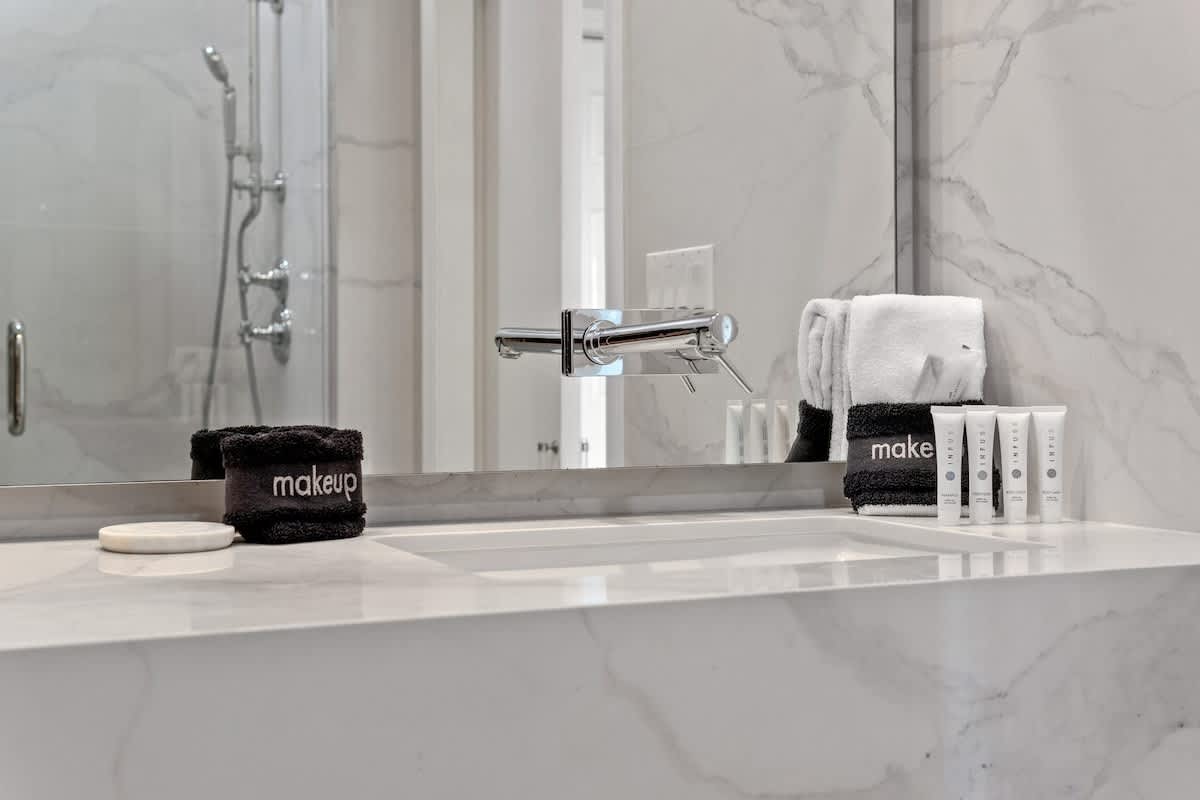 Inn at Seacrest 409 – Modern bathroom with marble counter, sink, towels, and toiletries displayed on a white shelf.