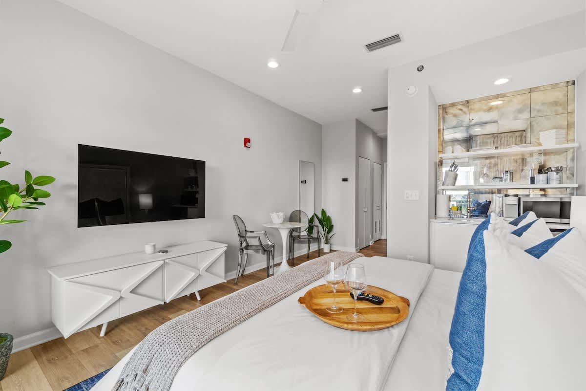 Inn at Seacrest 409 – Modern studio room with a bed, TV, small dining table, and kitchenette in light colors.