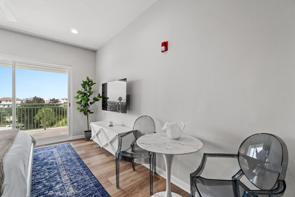 Inn at Seacrest 409 – Bright room featuring a bed, small round table with chairs, and a view through sliding glass doors.
