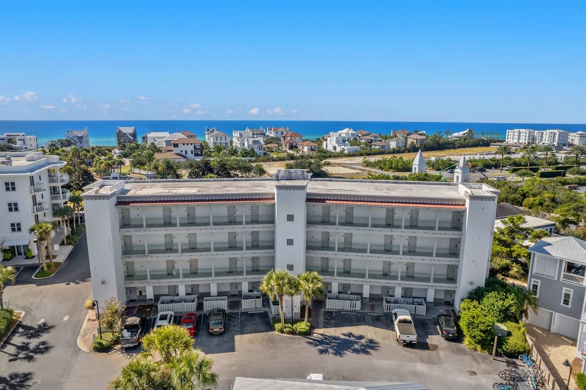 Inn at Seacrest 409 – Hotel exterior with three floors, palm trees, nearby residences, and ocean view in the background.