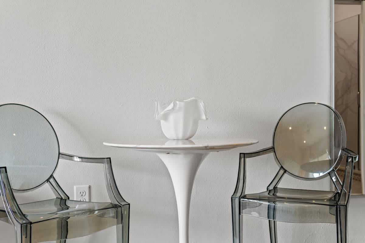 Inn at Seacrest 409 – Modern seating area with two transparent chairs and a round table featuring a decorative vase.