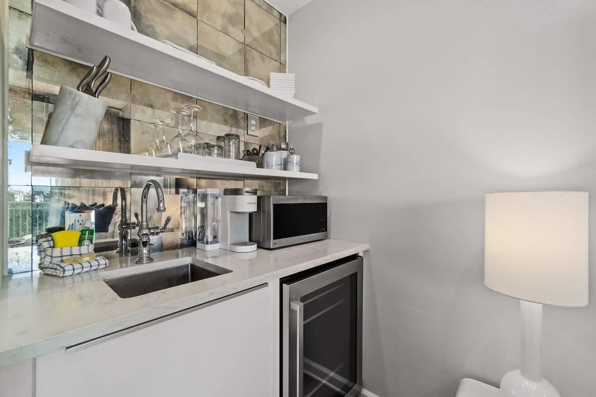 Inn at Seacrest 409 – Compact kitchenette with sink, microwave, coffee maker, and wine fridge against a stylish tiled wall.