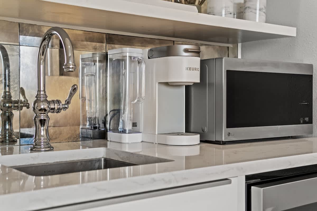 Inn at Seacrest 409 – Kitchenette with stainless steel faucet, Keurig coffee maker, and microwave on a marble countertop.