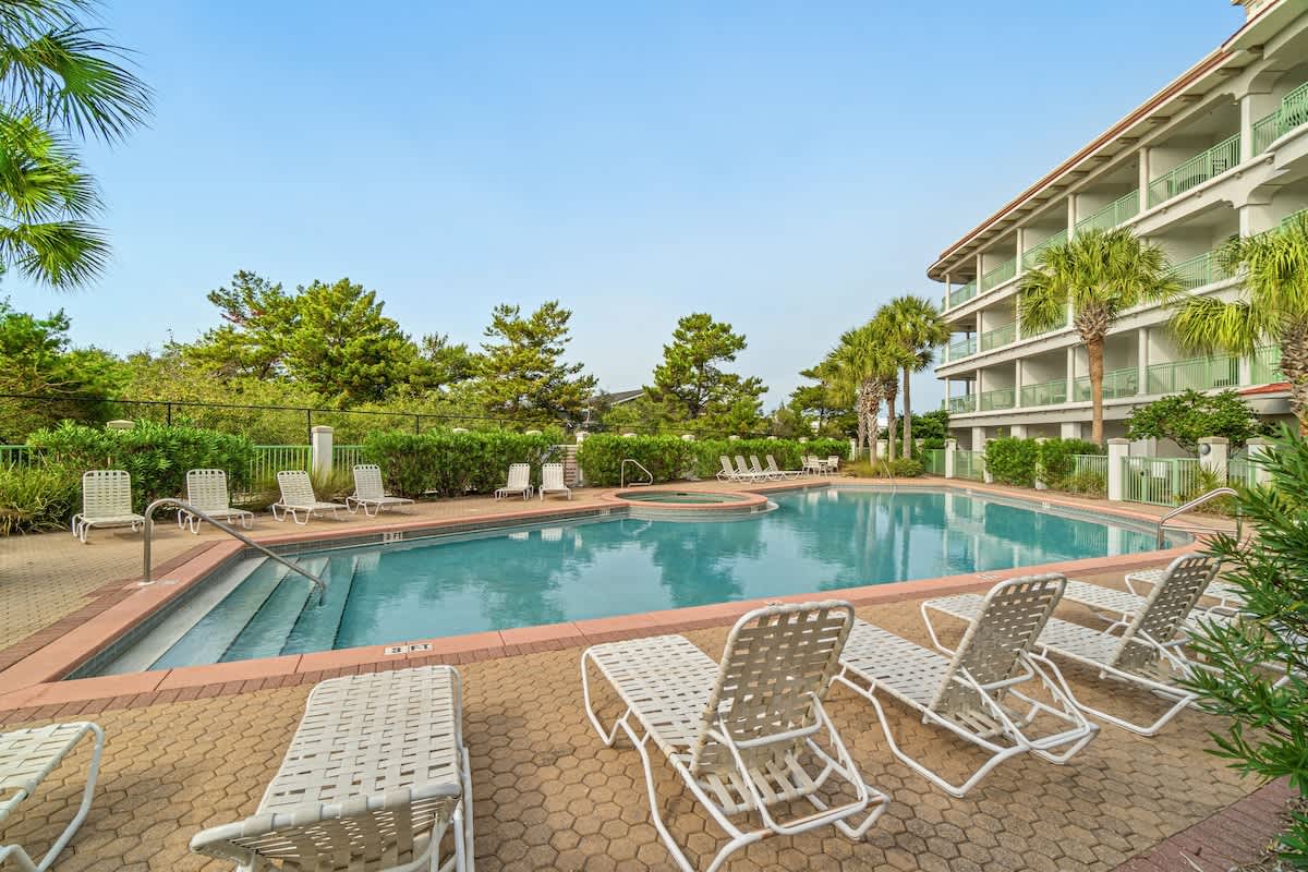 Inn at Seacrest 409 – Swimming pool surrounded by lounge chairs and palm trees, with a low-rise building in the background.