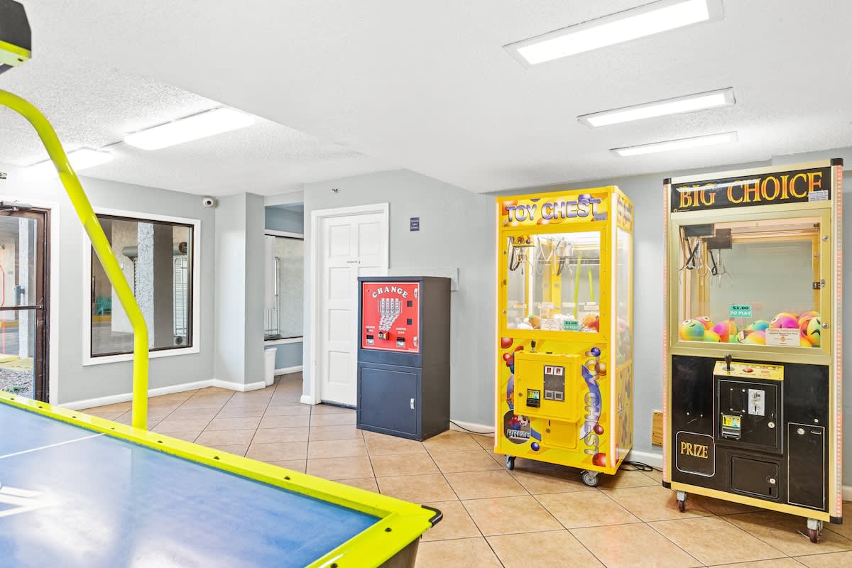 The Summit 1009 – Game room with air hockey table, claw machines, and vending machine in a tiled space.