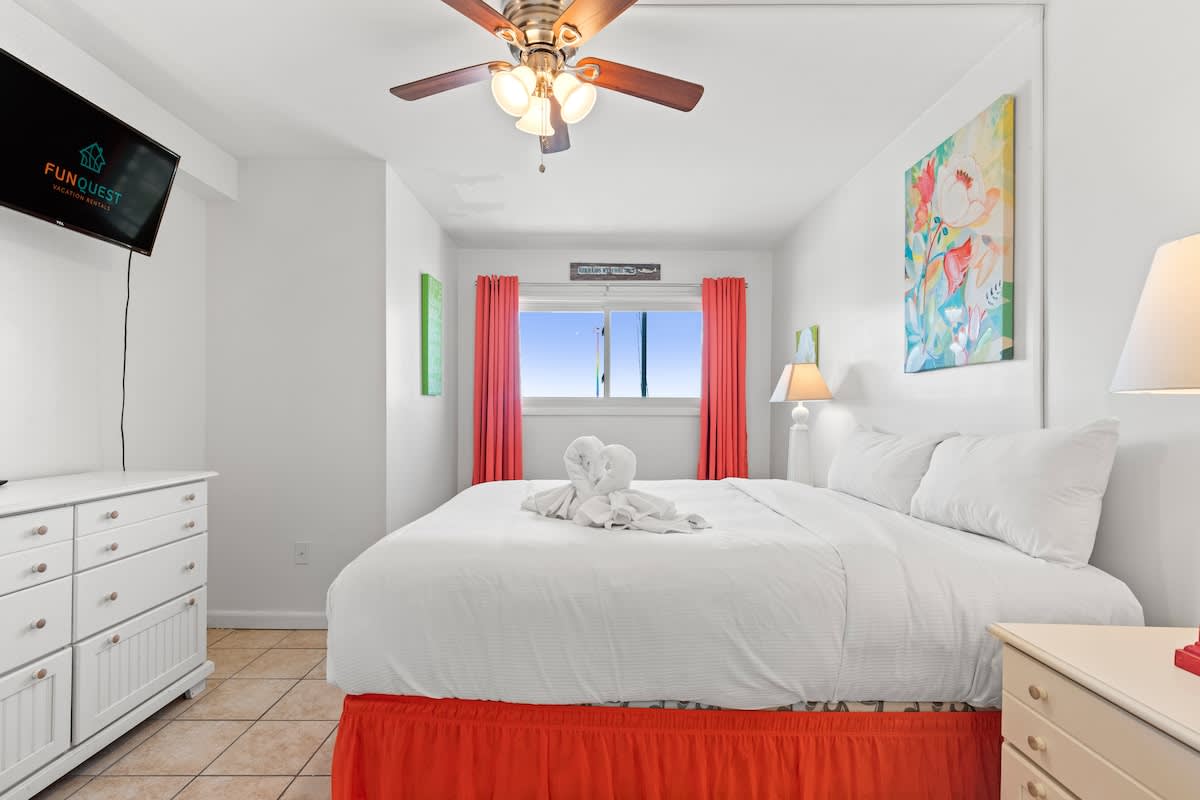 The Summit 1009 – Bedroom with a king-sized bed, wall-mounted TV, window with view, and decorative artwork.