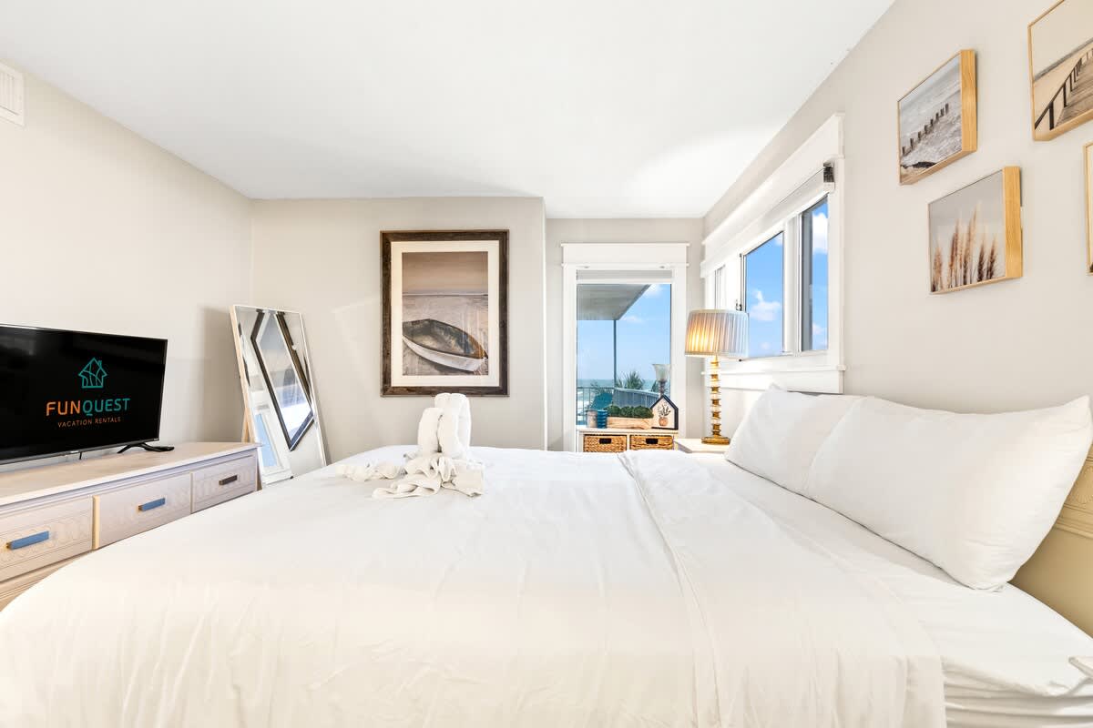 The Summit 301 – Cozy bedroom with queen bed, TV, and ocean view through large windows.