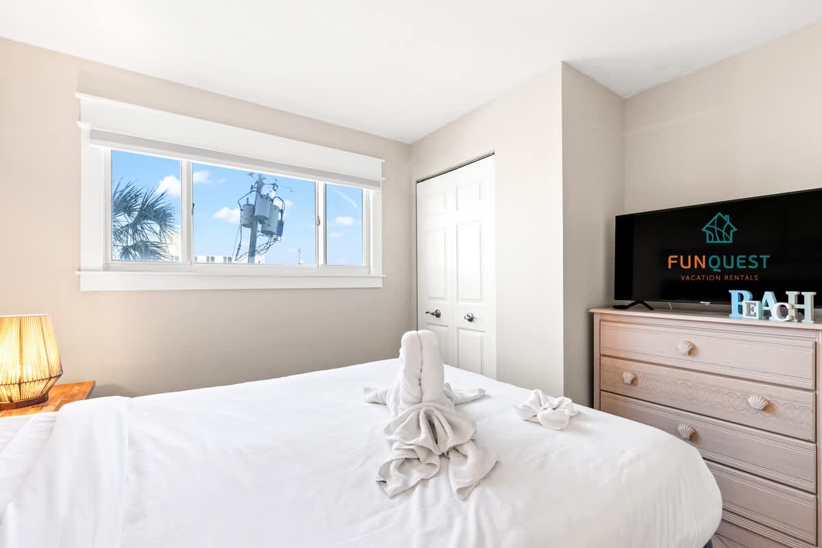 The Summit 301 – Bright bedroom with a window view, towel decorations on the bed, and a TV on a dresser.