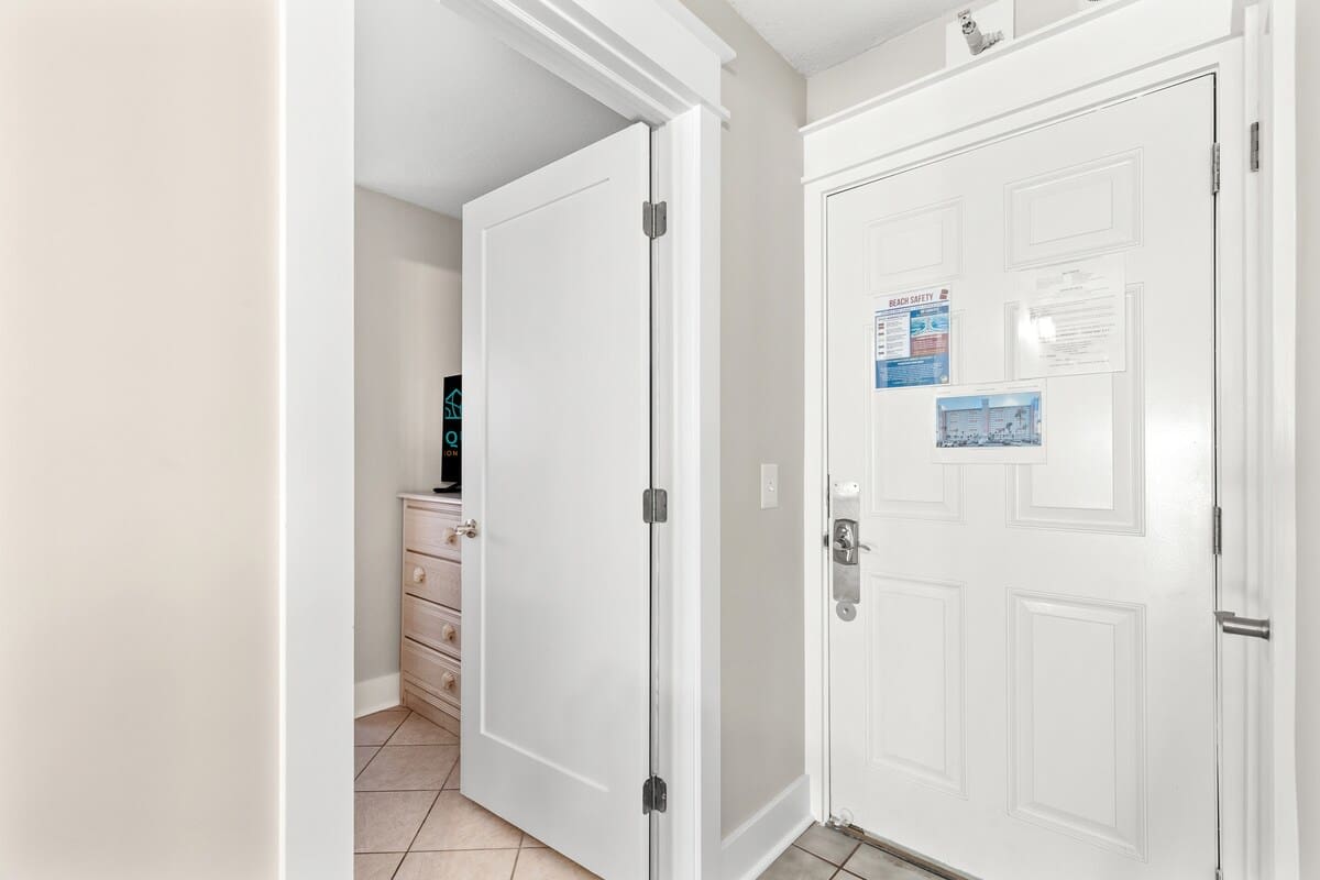 The Summit 301 – Entrance hallway with a closed door, light-colored walls, and a small dresser with a TV.