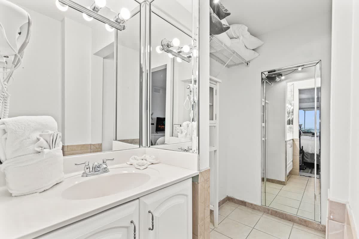 The Summit 301 – Bathroom with a vanity, large mirror, white towels, and access to an adjoining room.