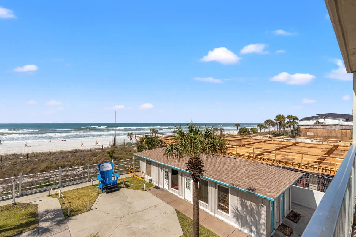 The Summit 301 – View of beach from a balcony, featuring sand, ocean waves, palm trees, and vacation rental exterior.