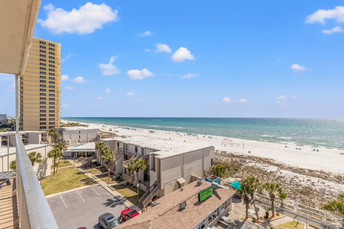 The Summit 632 – View from balcony overlooking beach, ocean, and nearby buildings with parking area below.