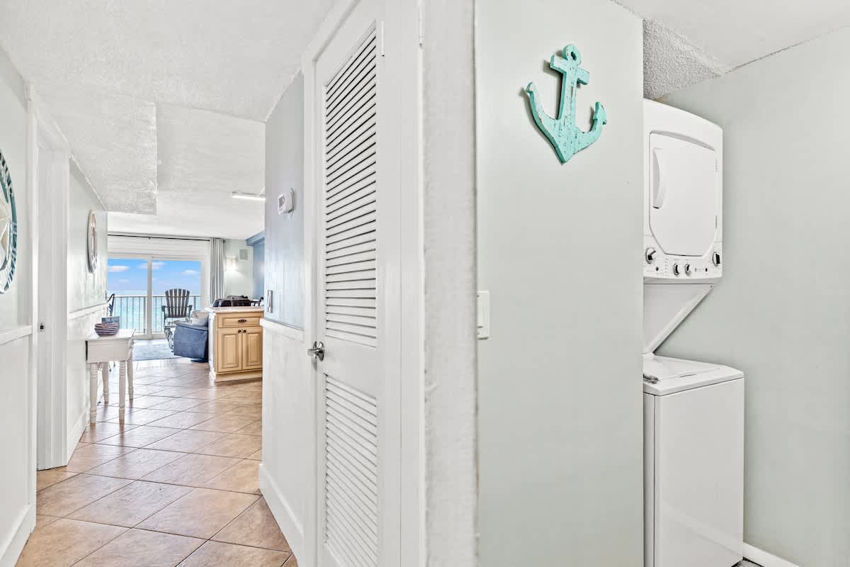 The Summit 632 – Hallway view with laundry appliances, leading to living area and balcony with ocean view.