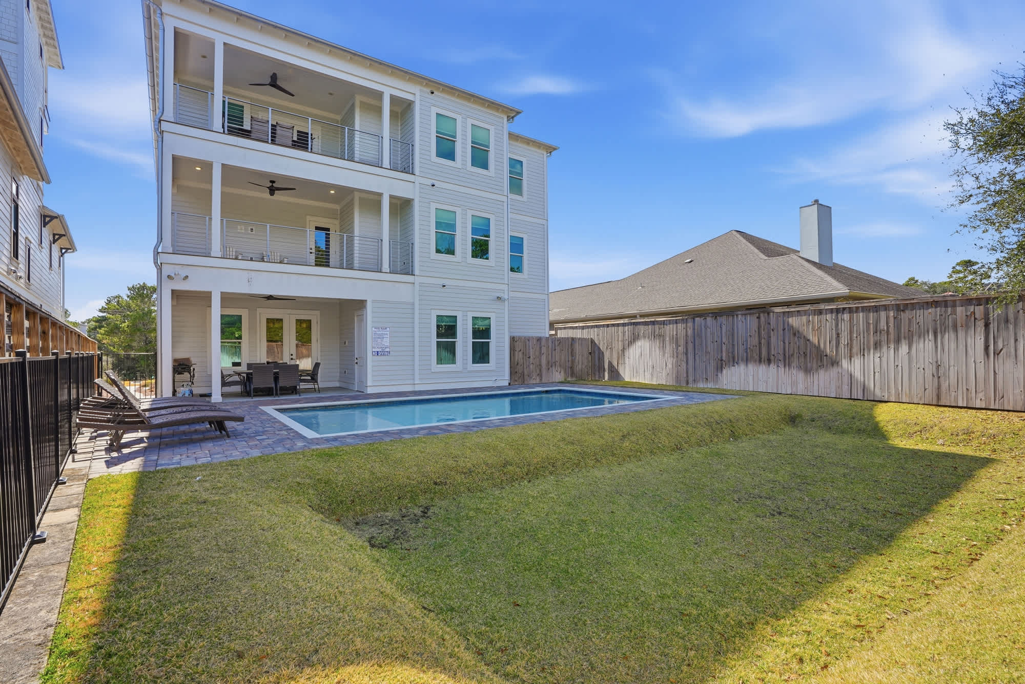 120 Dune Drive – Three-story vacation rental with pool, patio, and grass area, surrounded by a wooden fence.