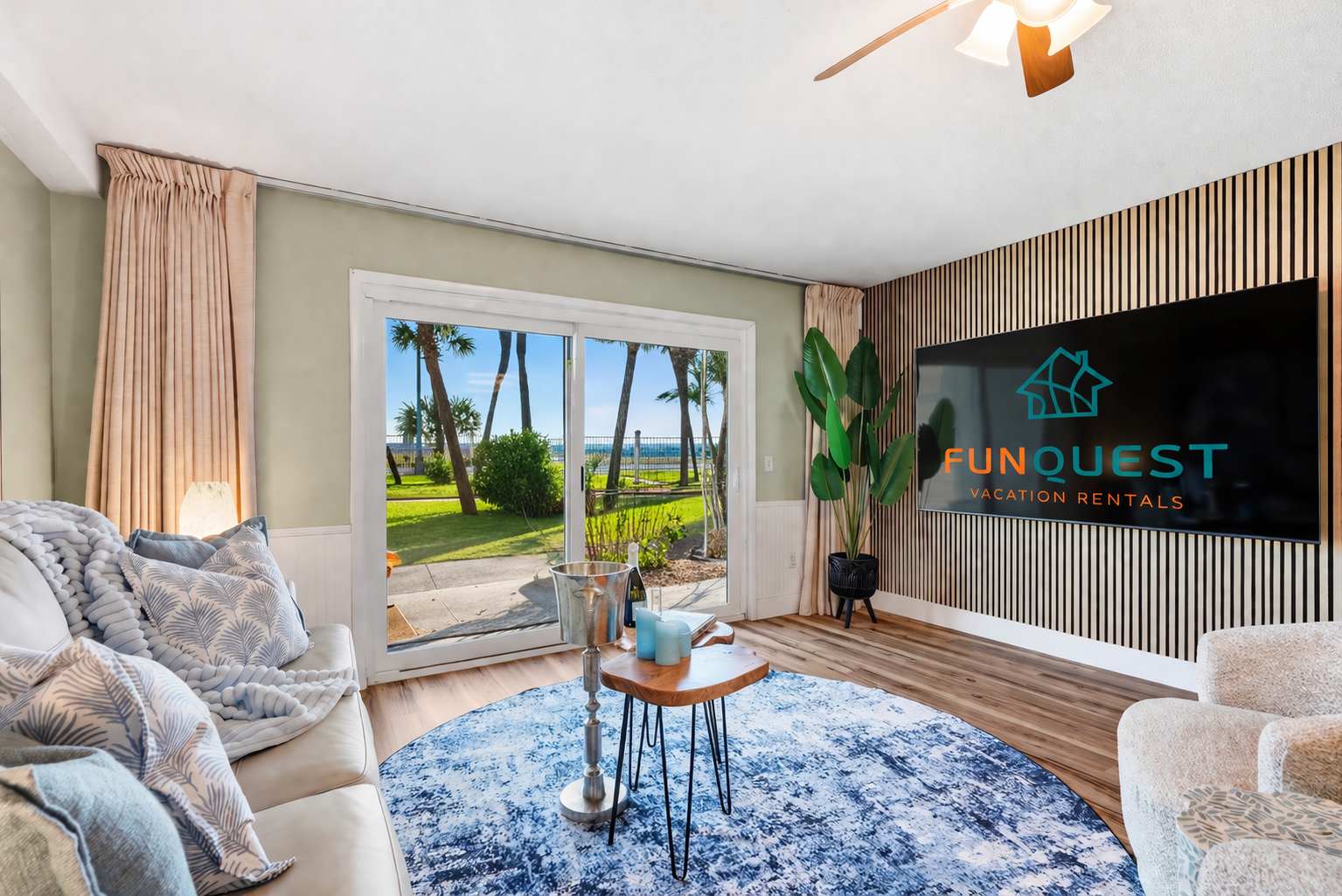 The Summit 131 – Cozy living room with sofa, area rug, and sliding glass doors opening to a palm tree view.