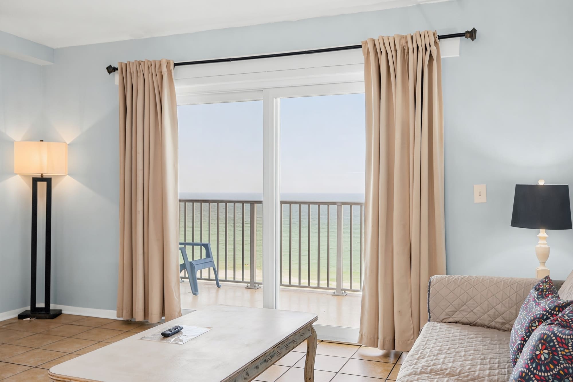 The Summit 1021 – Living room with ocean view, sliding glass doors, decorative pillows, lamp, and coffee table.
