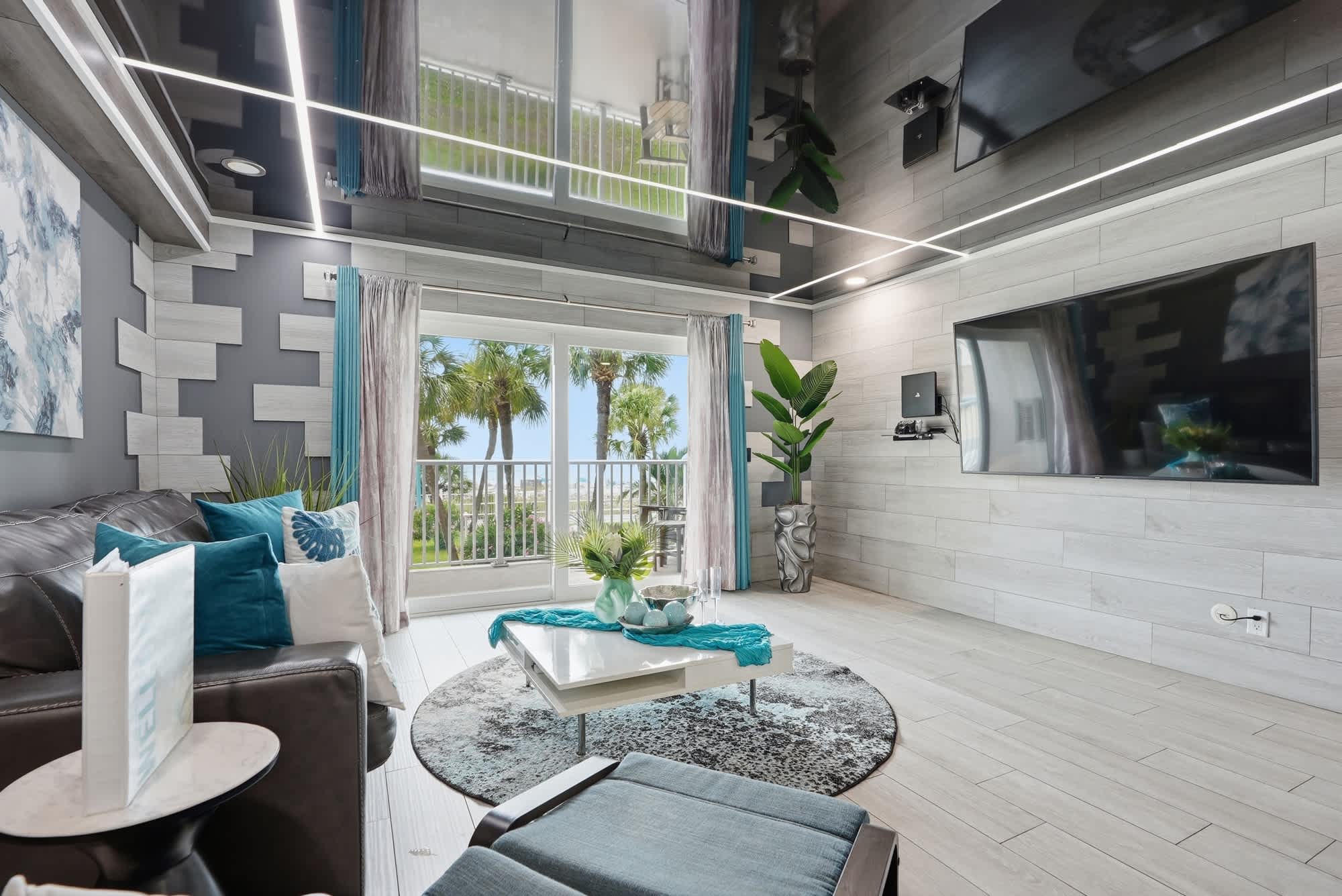 The Summit 231 – Stylish living room with large windows, palm tree view, modern decor, and seating area.