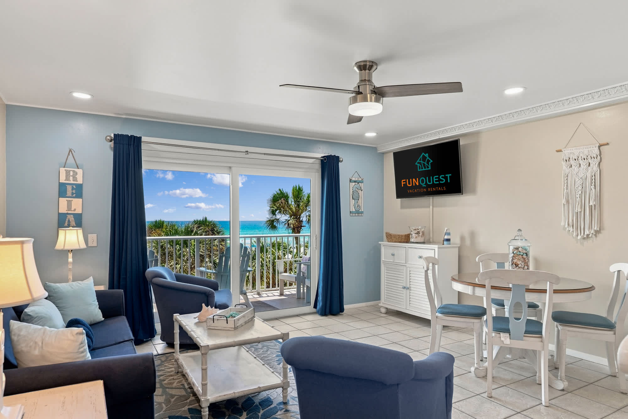 The Summit 308  – Bright living room with blue chairs, dining table, and ocean view balcony.