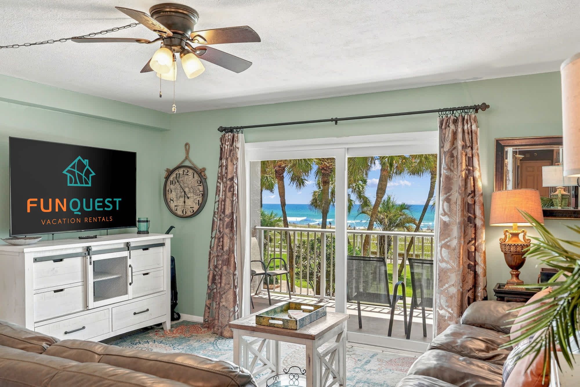 The Summit 225 – Living room with beach view, TV, ceiling fan, and balcony access.