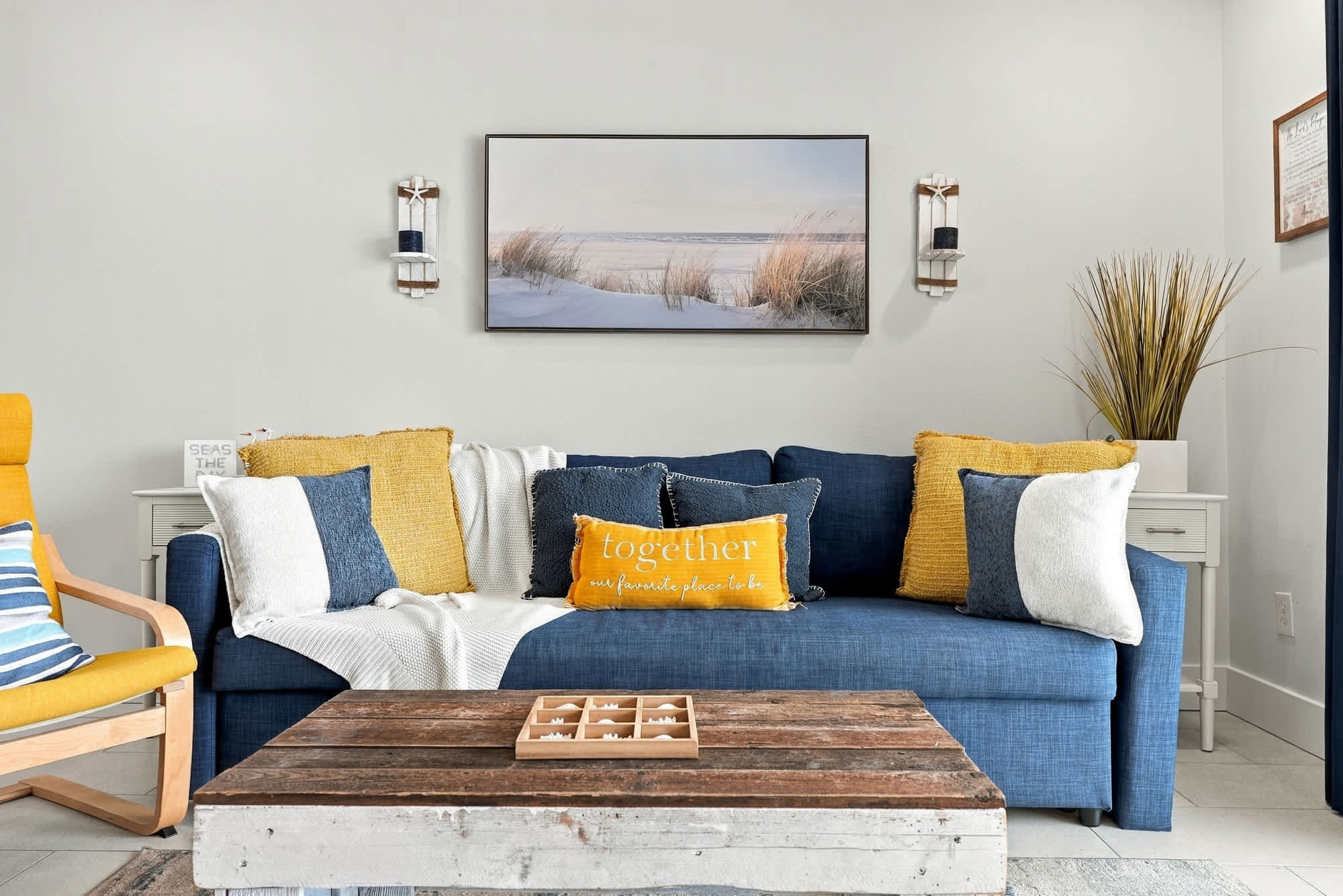 The Summit 1122  – Living room with blue couch, decorative pillows, wooden coffee table, and beach-themed wall art.