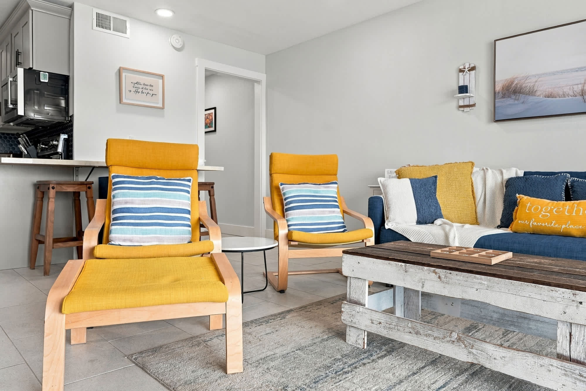 The Summit 1122  – Cozy living room with yellow chairs, blue sofa, wooden coffee table, and kitchen visible in the background.