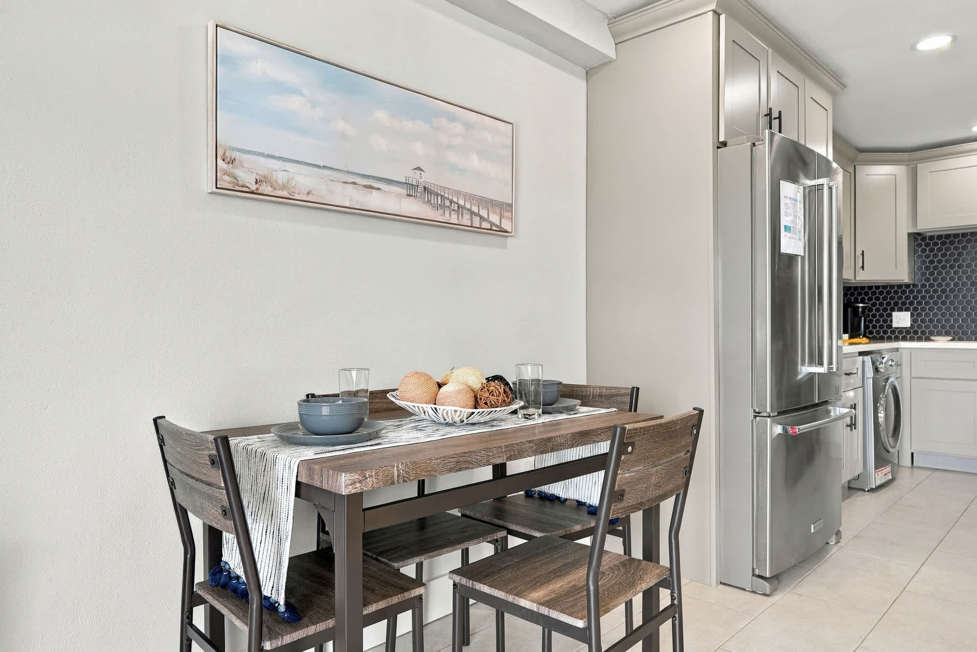 The Summit 1122  – Dining area with a wooden table, four chairs, and kitchen appliances in a modern rental.