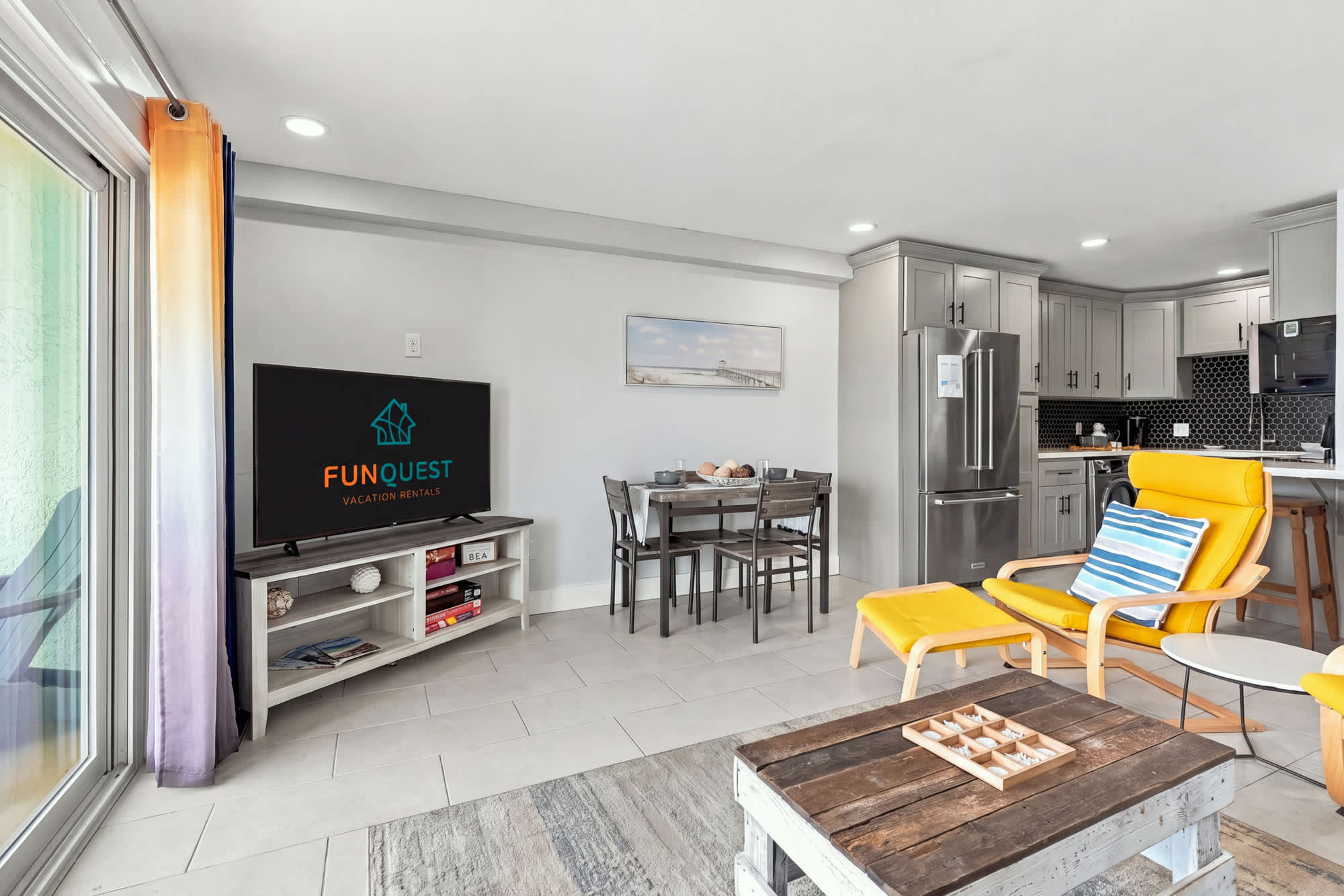 The Summit 1122  – Open living area with kitchen, dining table, yellow chair, and TV on a shelf.