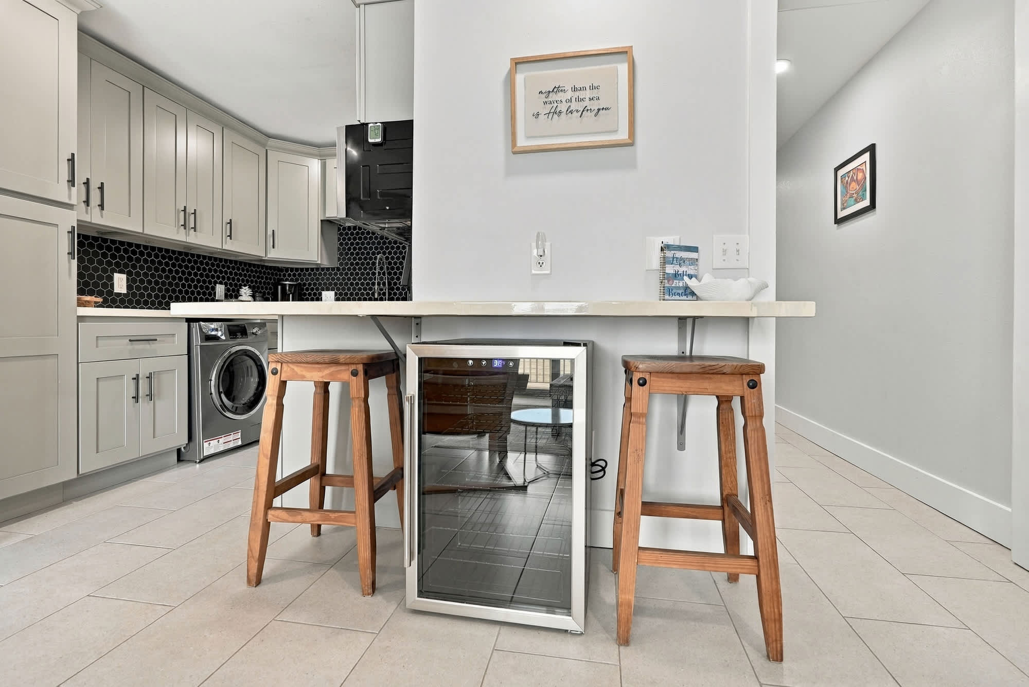 The Summit 1122  – Modern kitchen with light gray cabinetry, bar stools, wine cooler, and laundry machine.