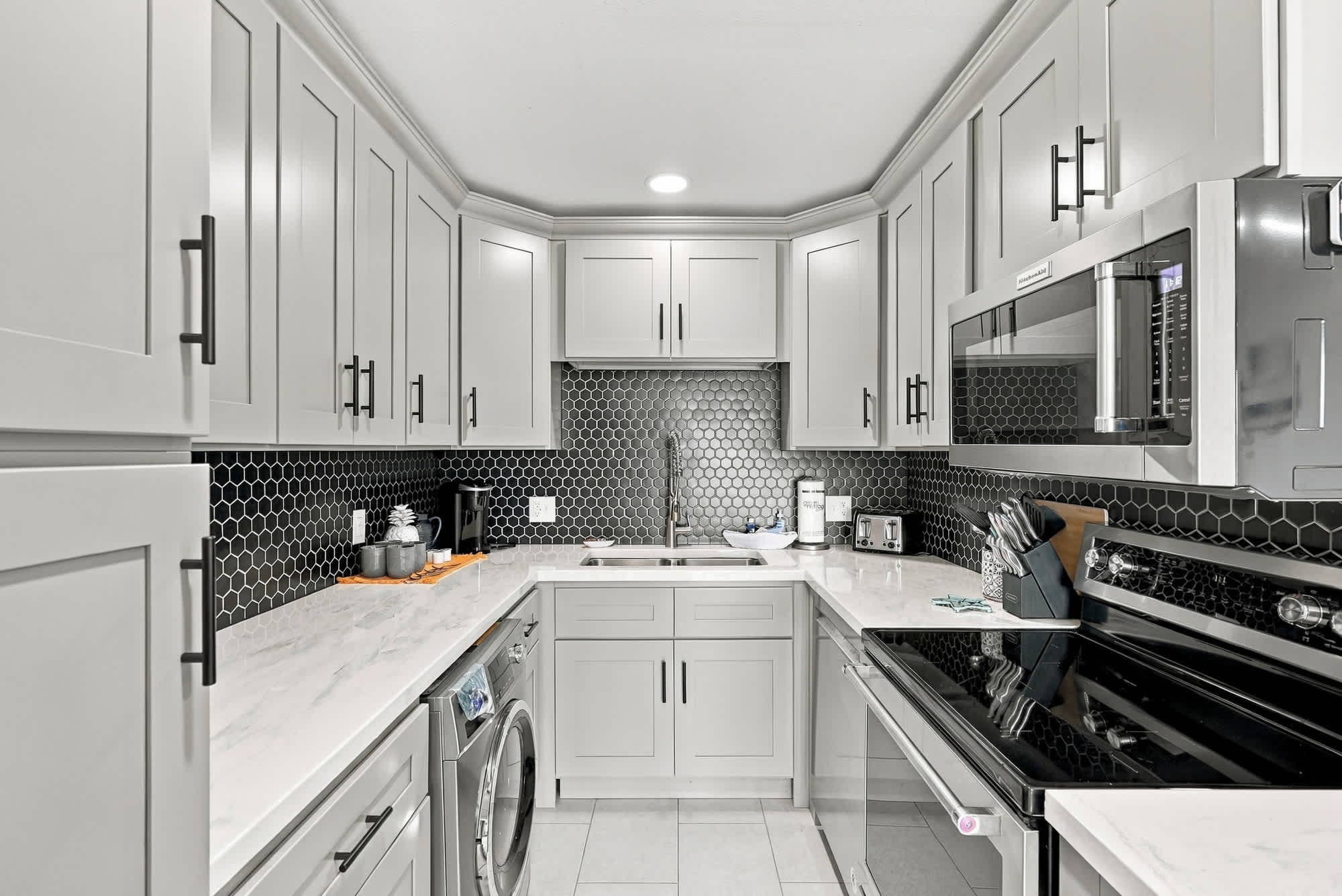 The Summit 1122  – Modern kitchen with gray cabinets, black hexagonal backsplash, stainless steel appliances, and washer/dryer.
