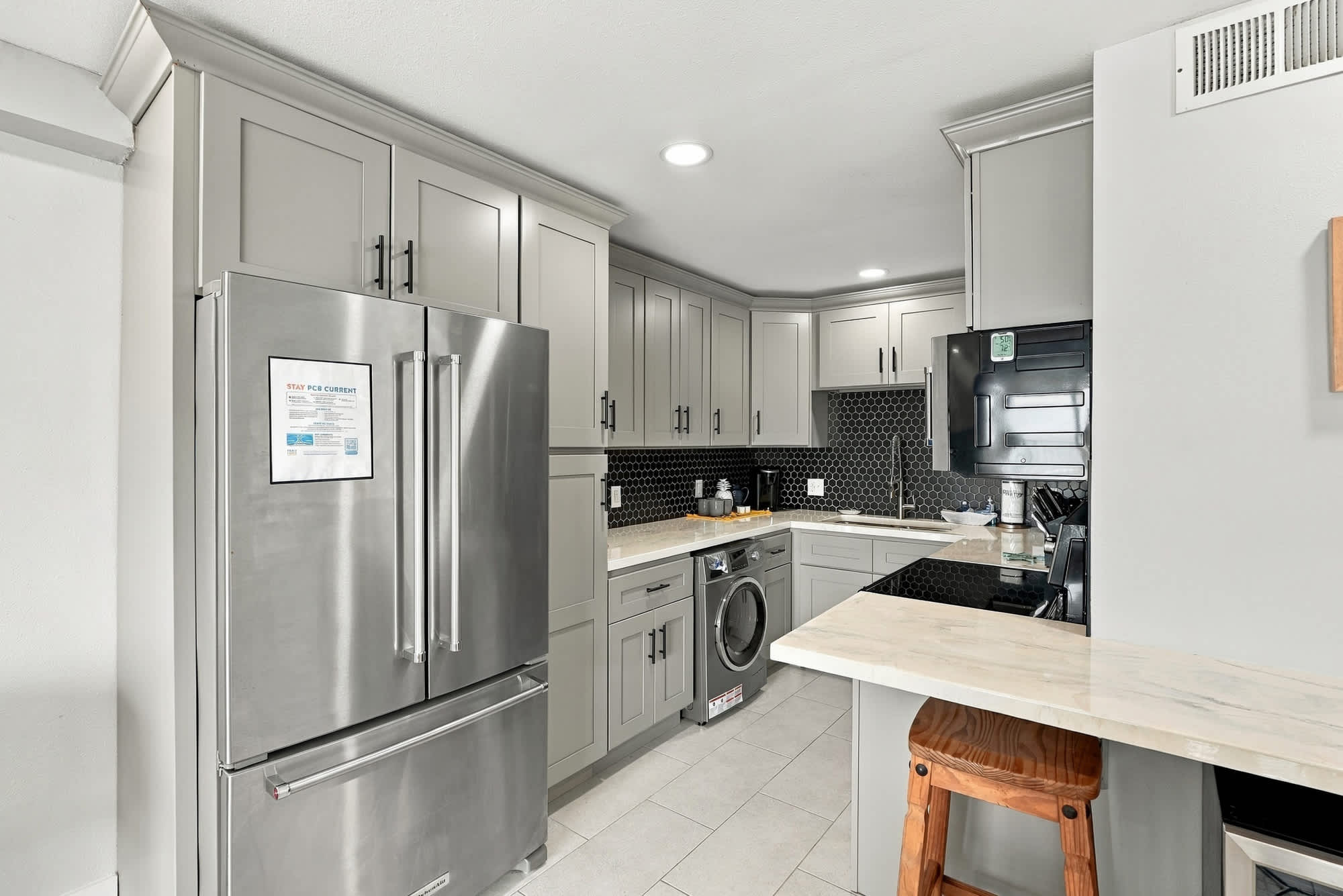 The Summit 1122  – Modern kitchen with stainless steel appliances, gray cabinetry, black backsplash, and small breakfast bar.