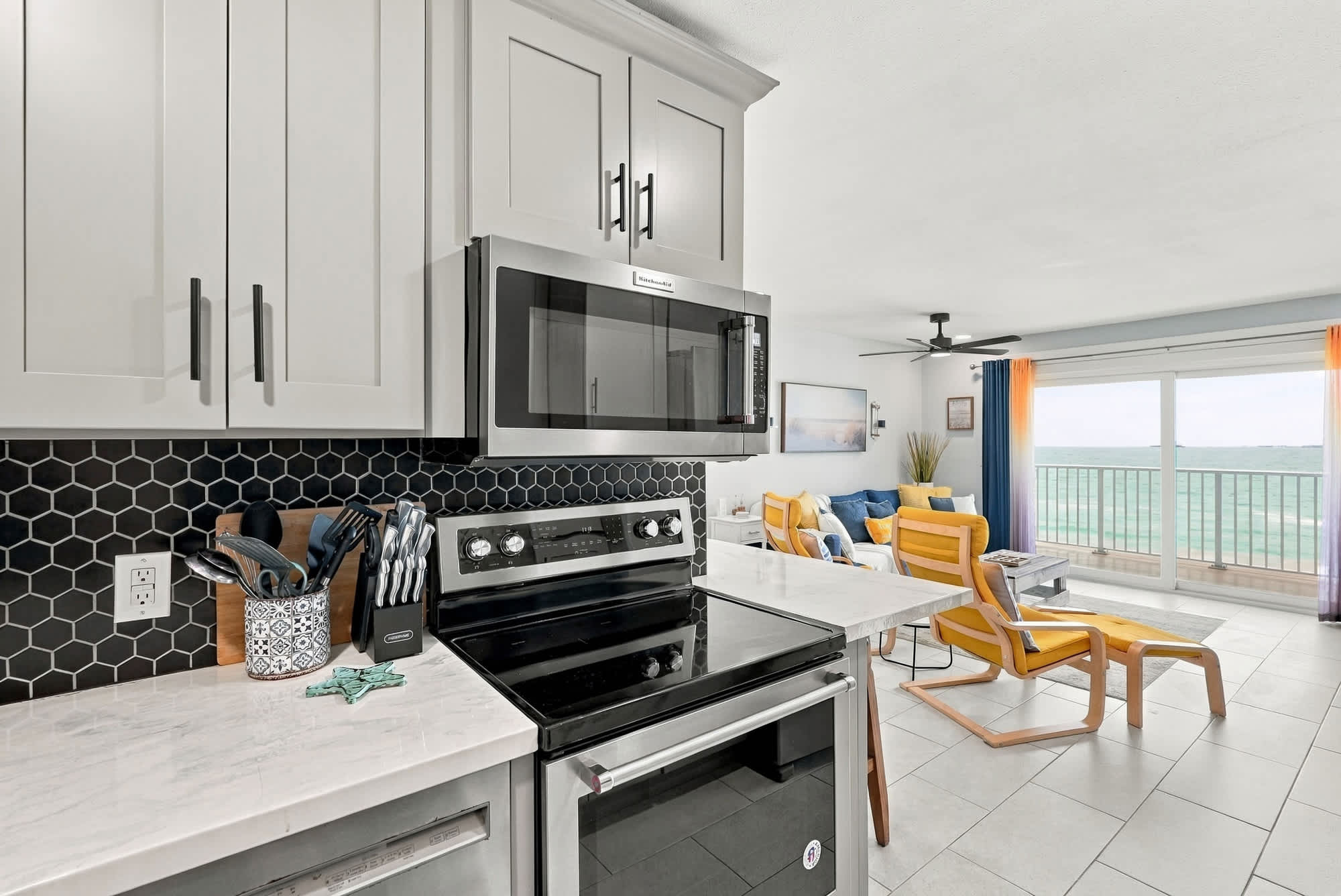 The Summit 1122  – Modern kitchen with stainless appliances, living area featuring colorful seating and ocean view through large windows.