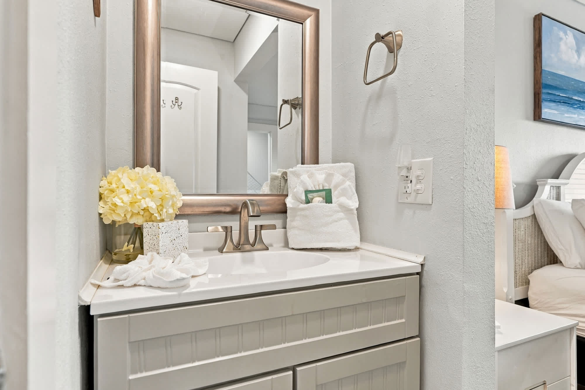 The Summit 1122  – Bathroom with a white sink, large mirror, decorative flower, and towels on the counter.