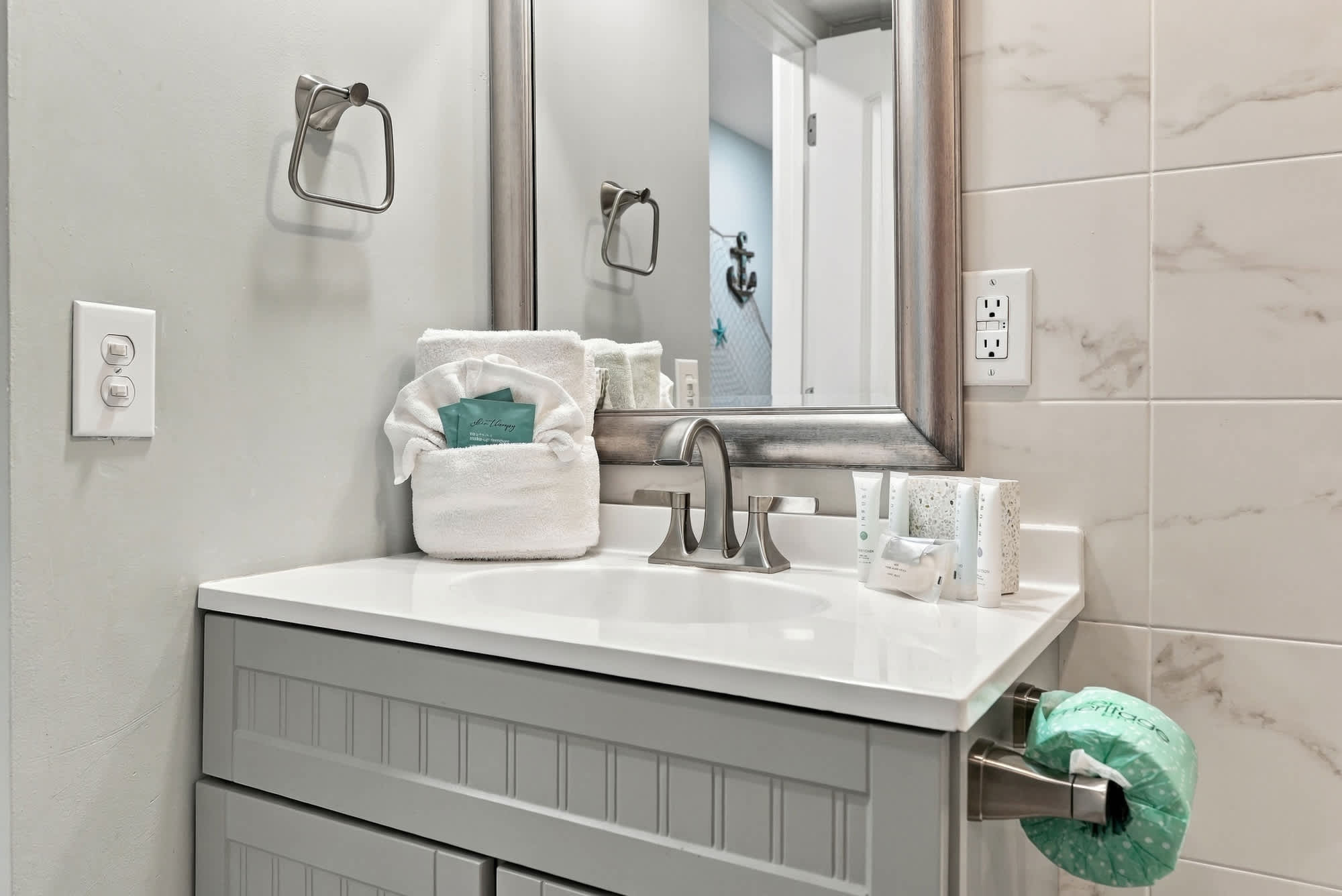 The Summit 1122  – Modern bathroom with a gray vanity, mirror, and toiletries on a white countertop.