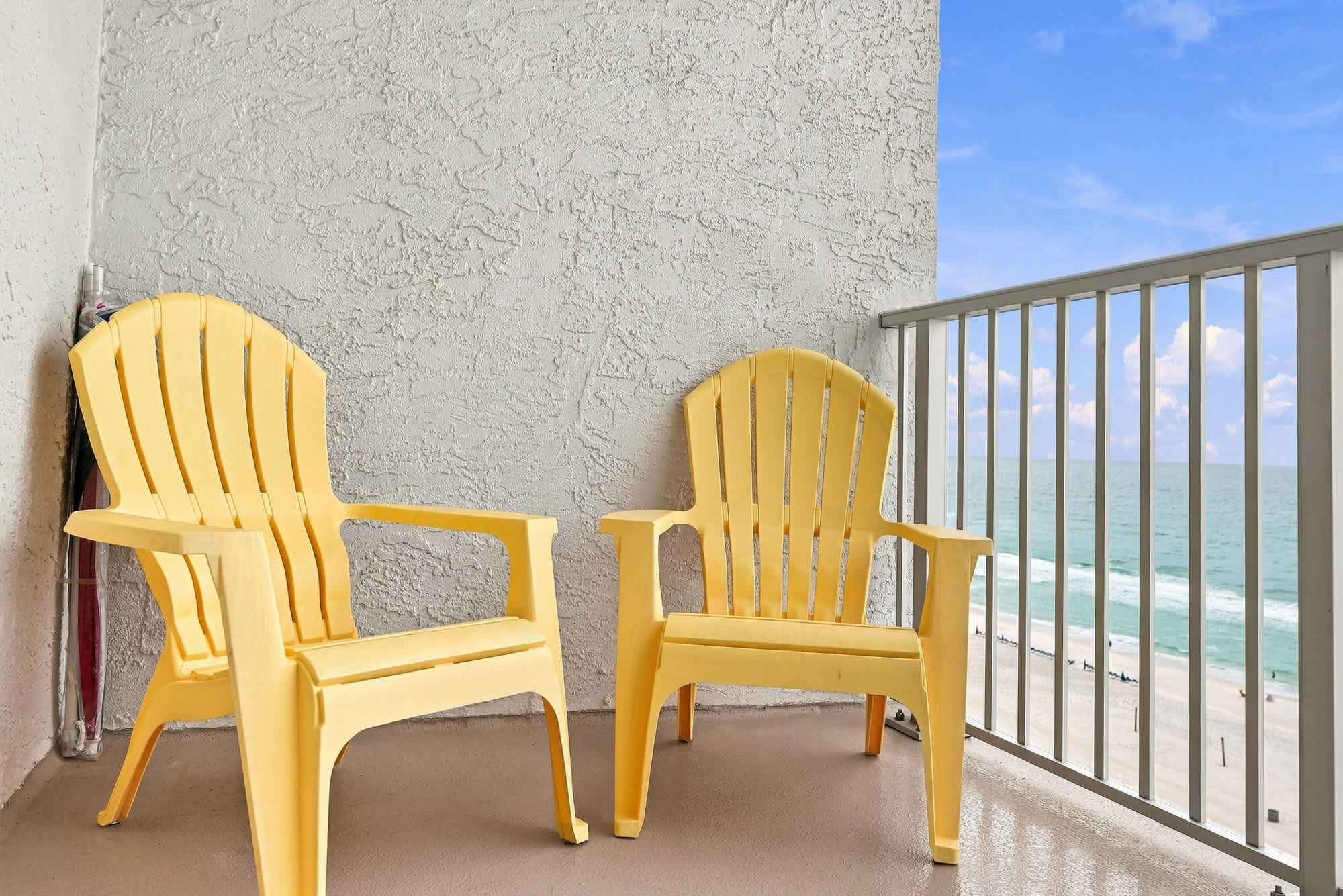 The Summit 1122  – Two yellow Adirondack chairs on a balcony with an ocean view.