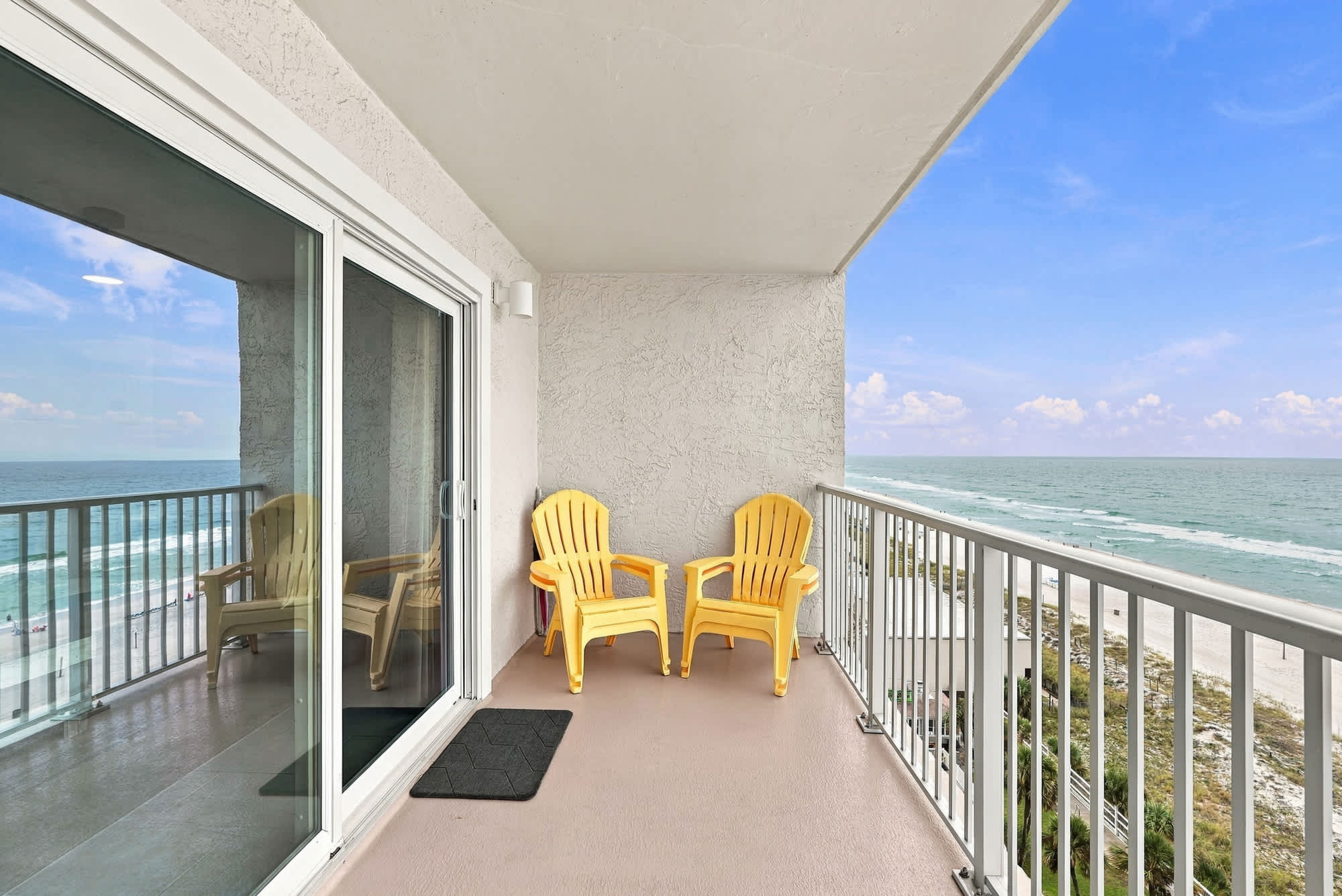 The Summit 1122  – Balcony with two yellow chairs overlooking the ocean and sandy beach.