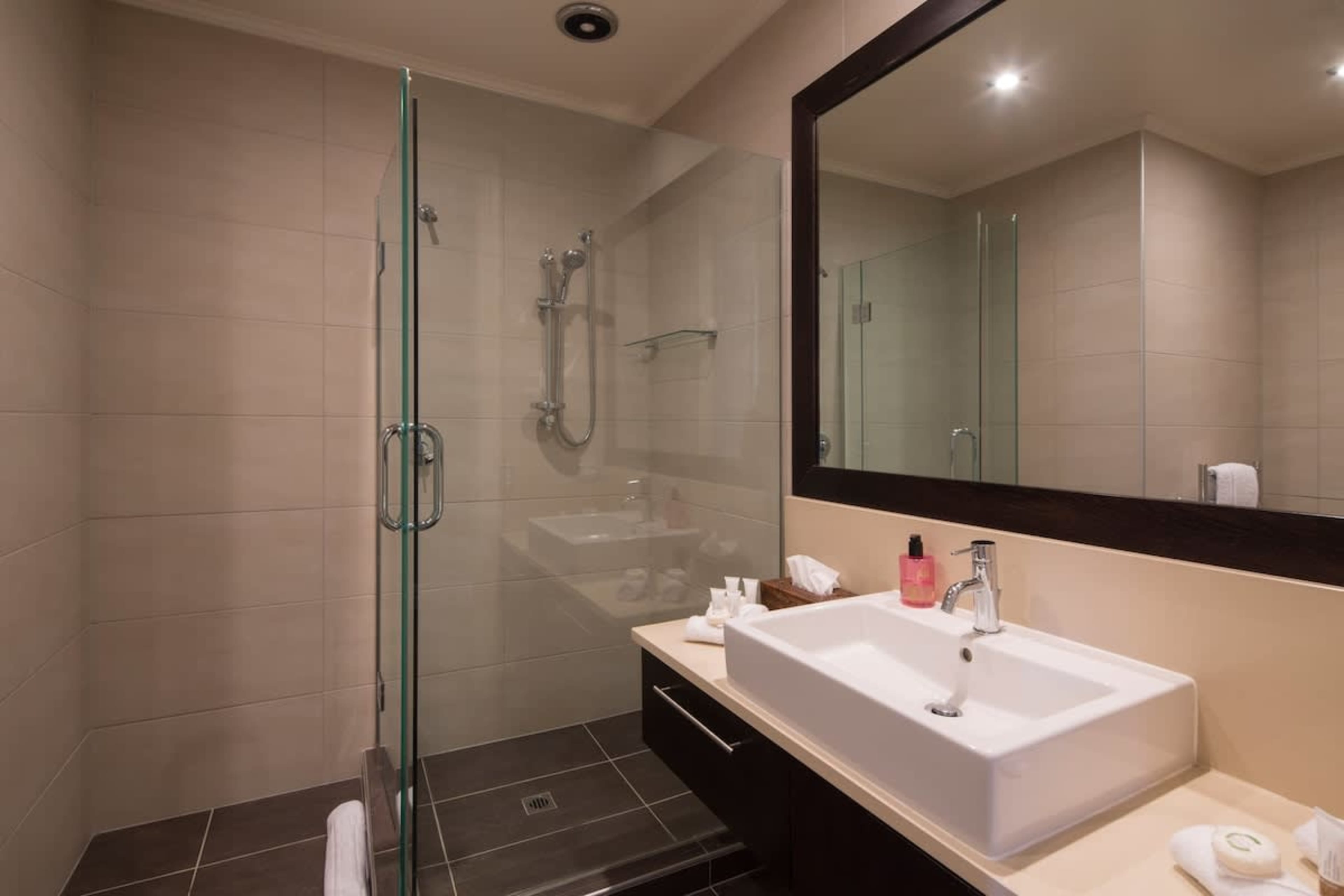 Modern Shared Bathroom: Featuring a sleek walk-in shower and stocked with luxurious Ashley & Co toiletries for a refreshing experience.