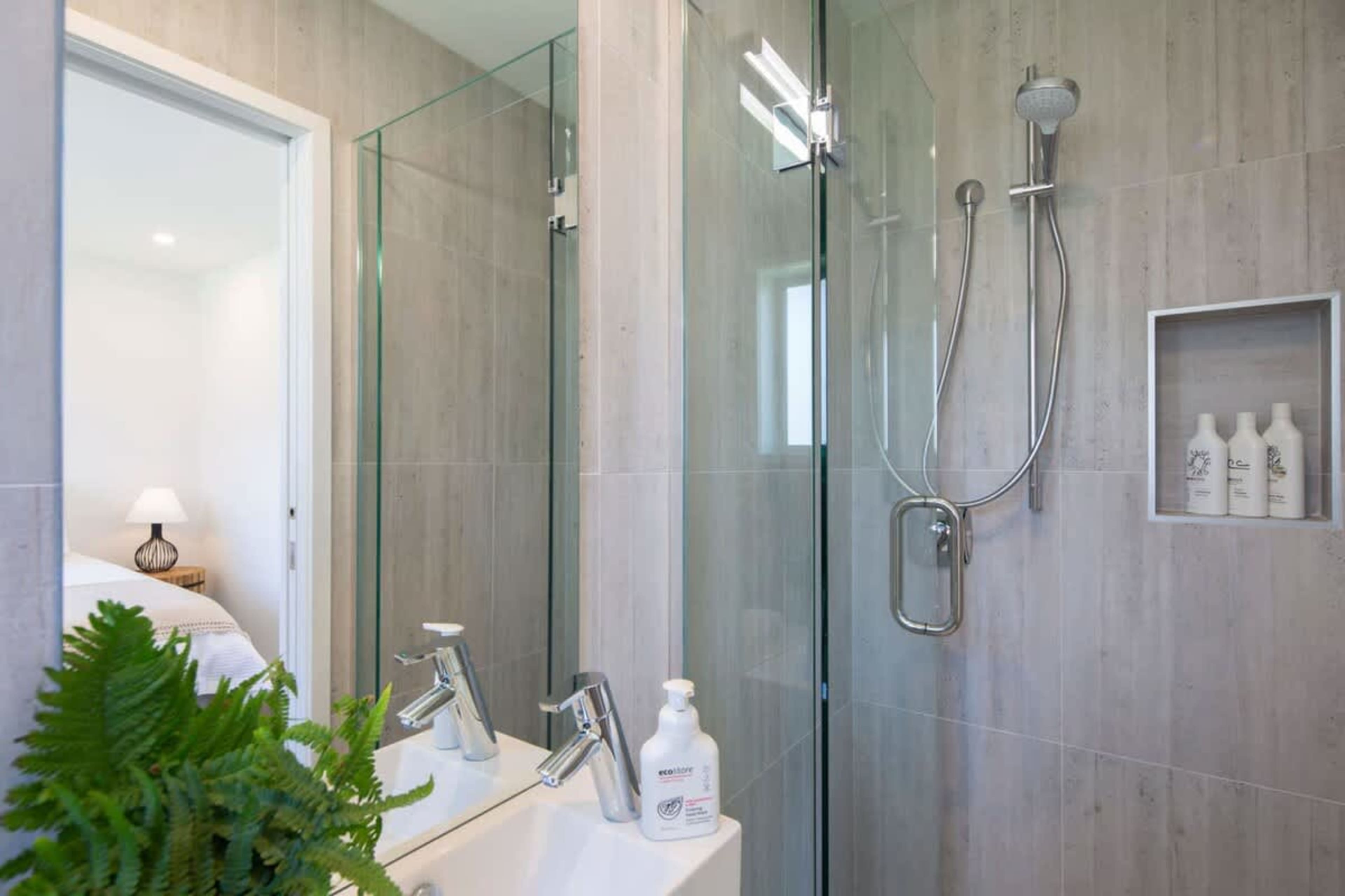 This modern bathroom features a walk-in shower, underfloor heating for added comfort, and is conveniently connected to the second bedroom. It offers a relaxing, private space with stylish finishes and thoughtful amenities.