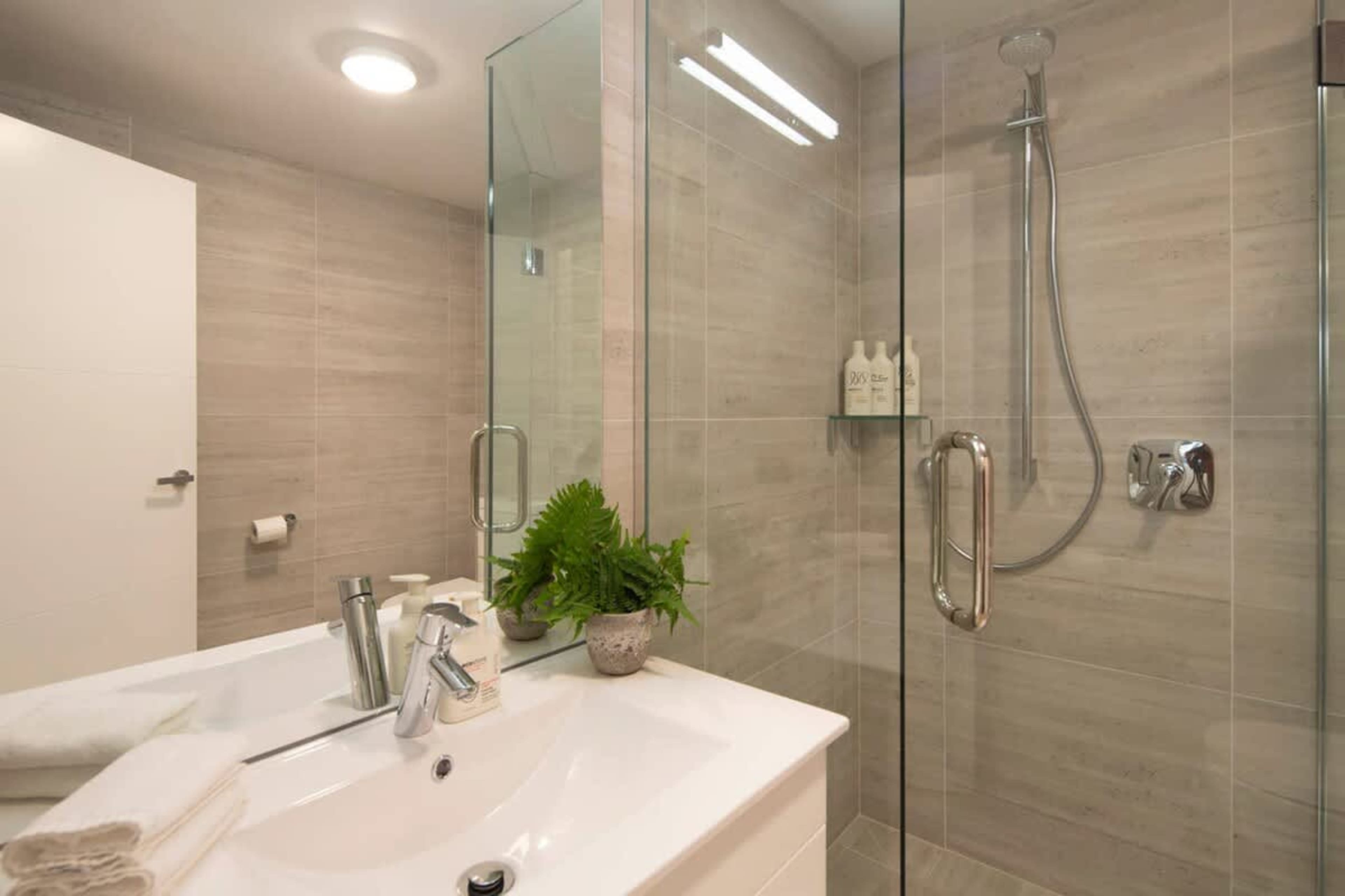 This modern bathroom features a walk-in shower, luxurious underfloor heating, and premium Ashley & Co. toiletries. Designed for comfort and relaxation, it offers a warm, indulgent space to refresh after a day of exploring Queenstown.