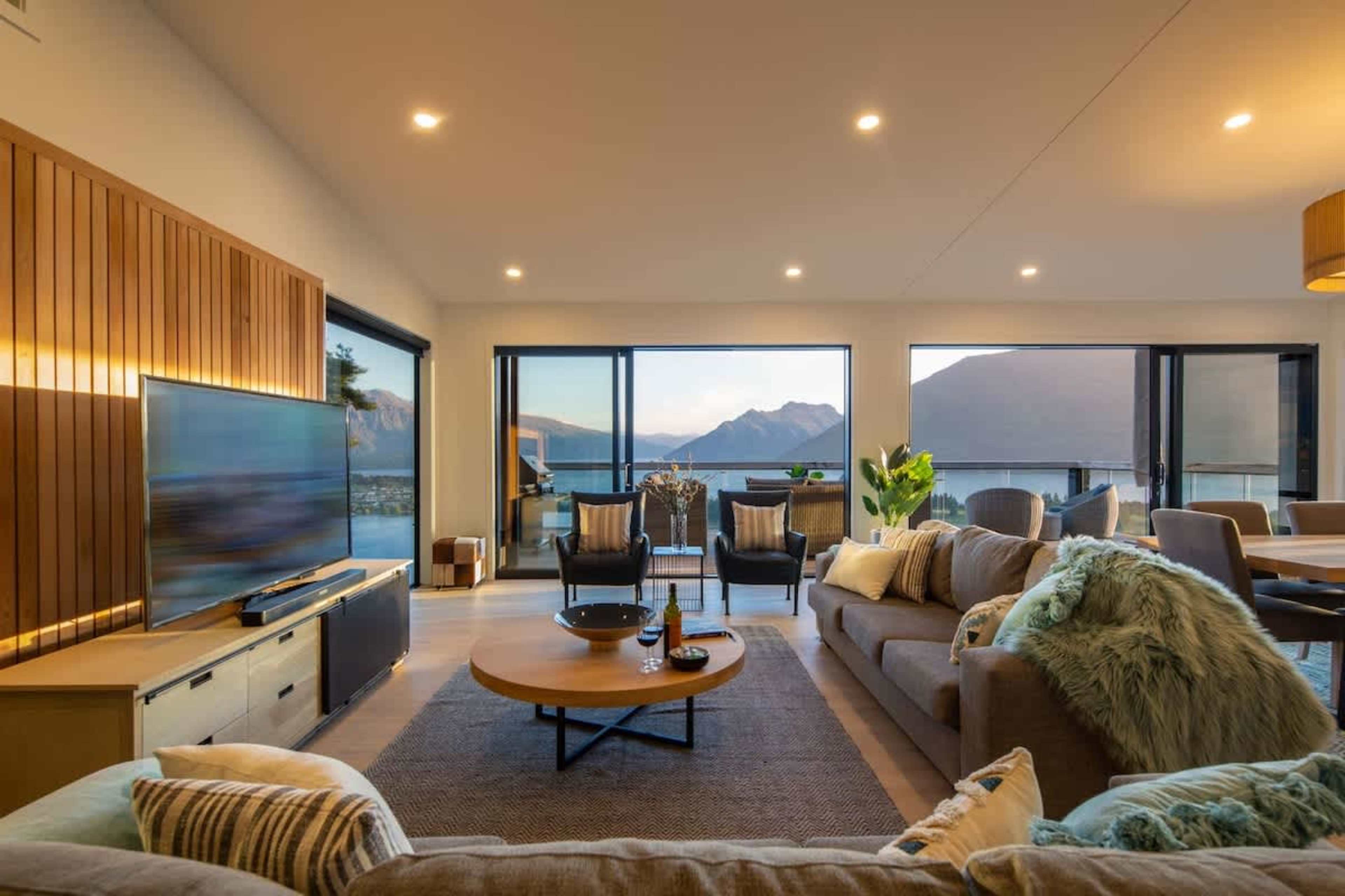 Stylish Living Room with Expansive Views – Relax in this beautifully decorated living space, featuring large windows that provide breathtaking views of the lake and mountains, creating a tranquil ambiance for unwinding after a day of adventure.