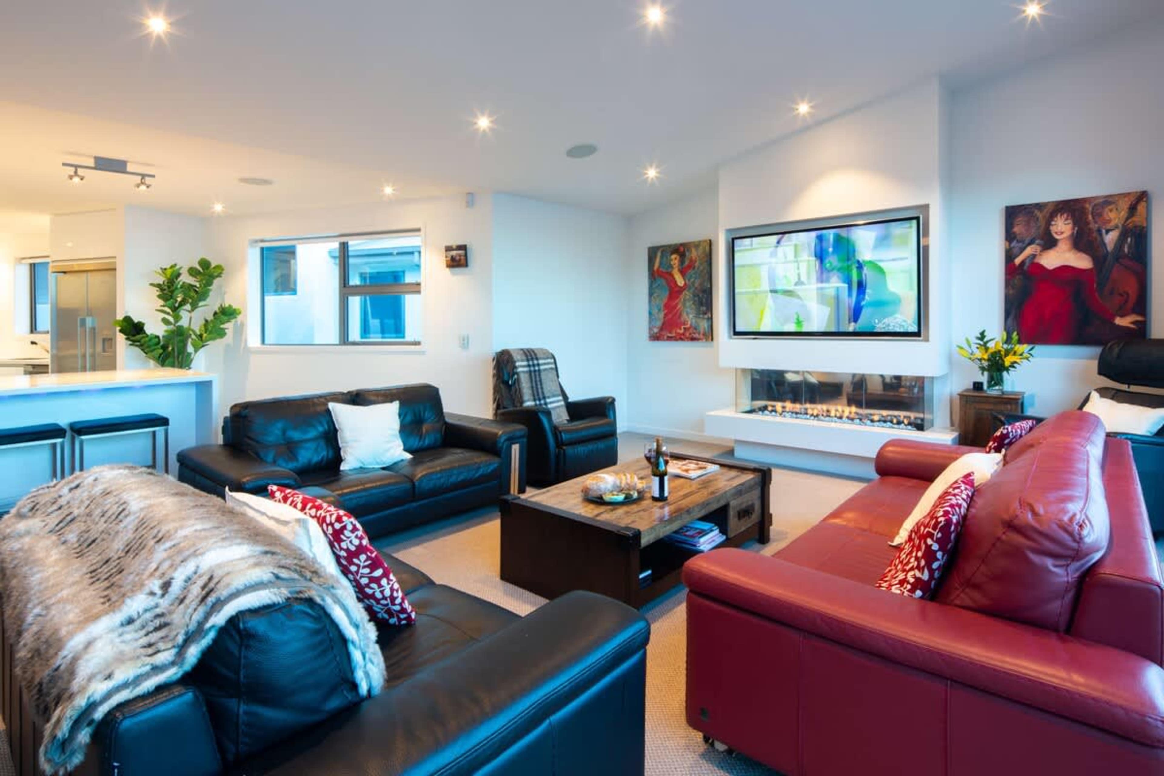Open-Plan Living Room with Modern Fireplace – Gather in a stylish, spacious setting featuring a cozy fireplace, perfect for entertaining or relaxing after a day exploring Queenstown.
