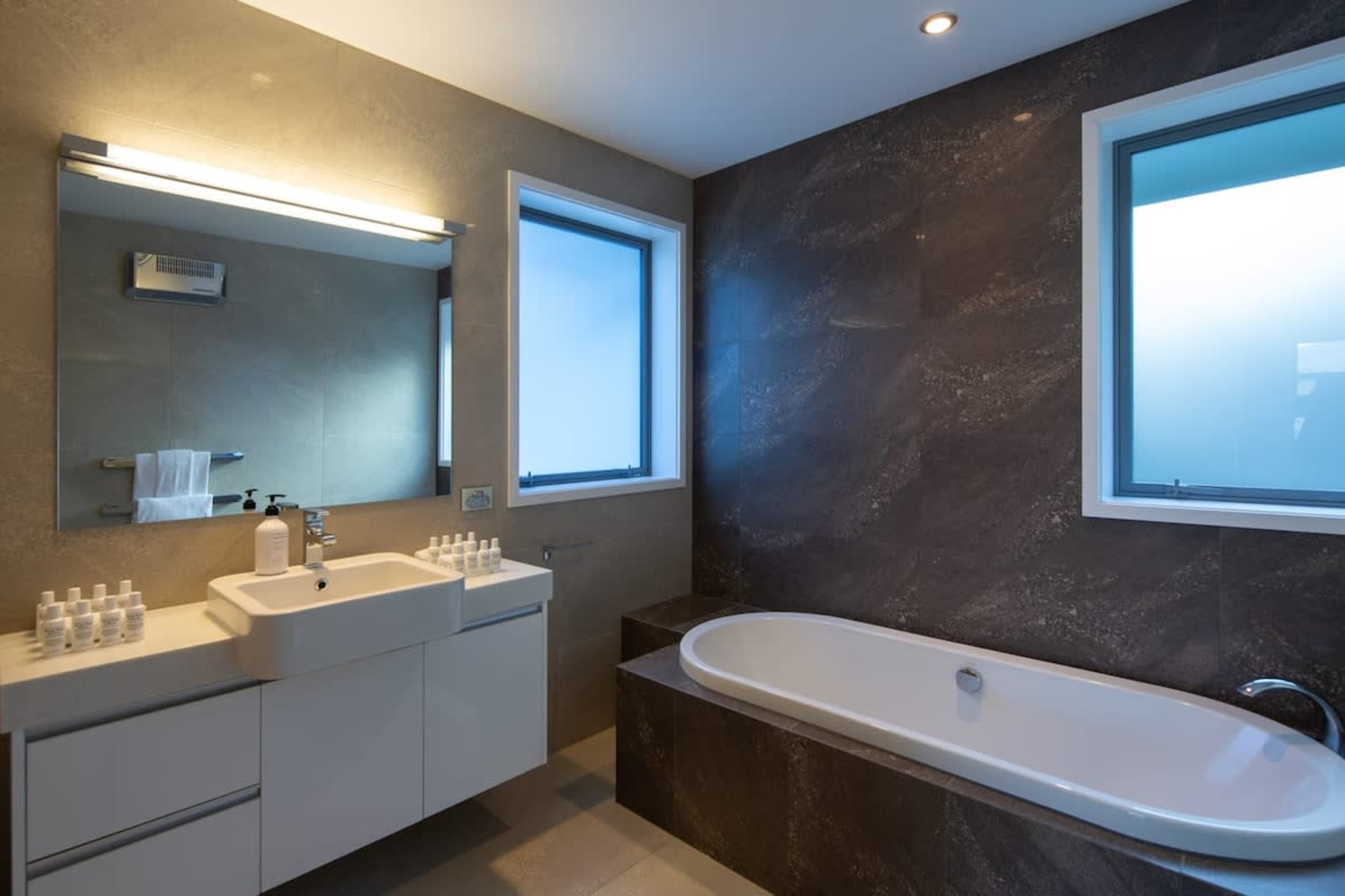 Luxurious Bathroom with Bathtub and Premium Toiletries – Indulge in a spa-like experience with a deep-soaking bathtub, complemented by Ashley & Co. and Brown premium toiletries for ultimate relaxation.