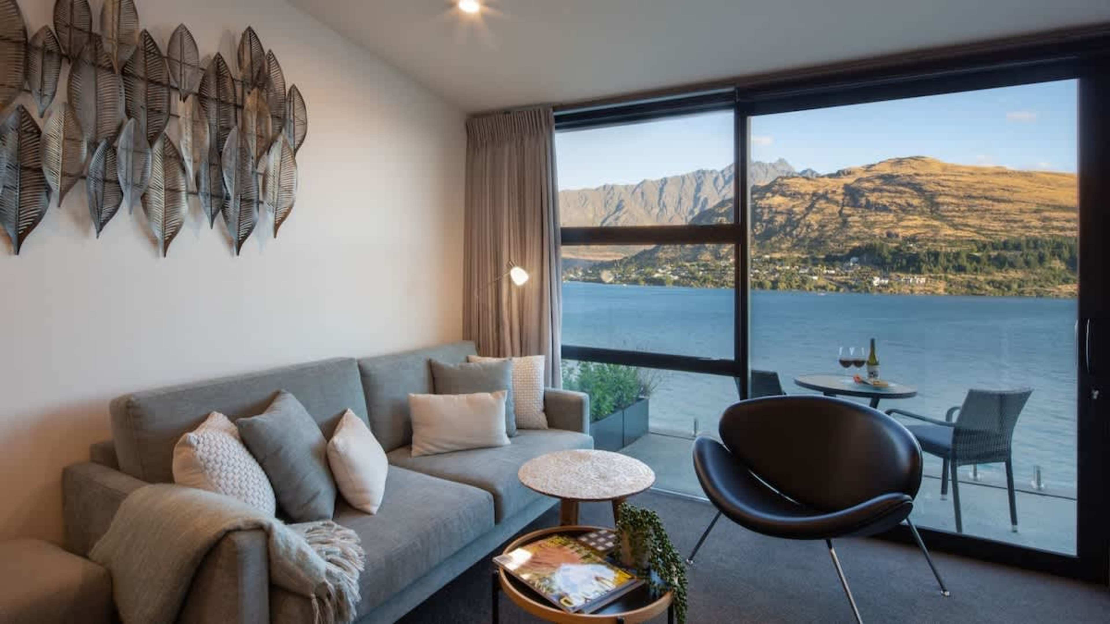 Serene Lakefront Living – Unwind in this peaceful living room, offering panoramic views of Lake Wakatipu, creating a tranquil atmosphere with modern comforts for the perfect lakeside retreat.