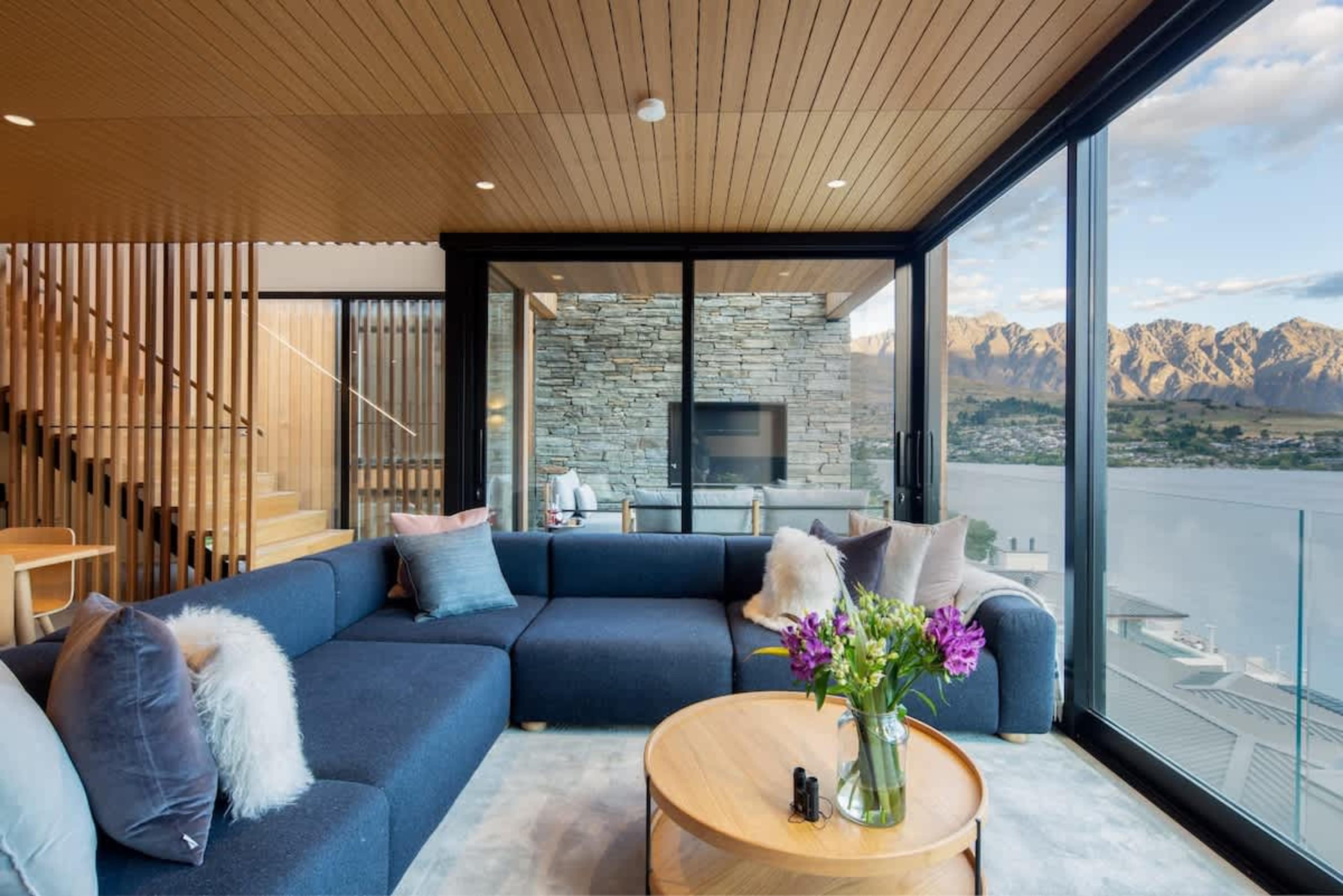 Inviting Living Room with Fireplace and Views – Relax in this beautifully appointed living room, with a crackling fireplace and large windows framing amazing views of the lake and mountains